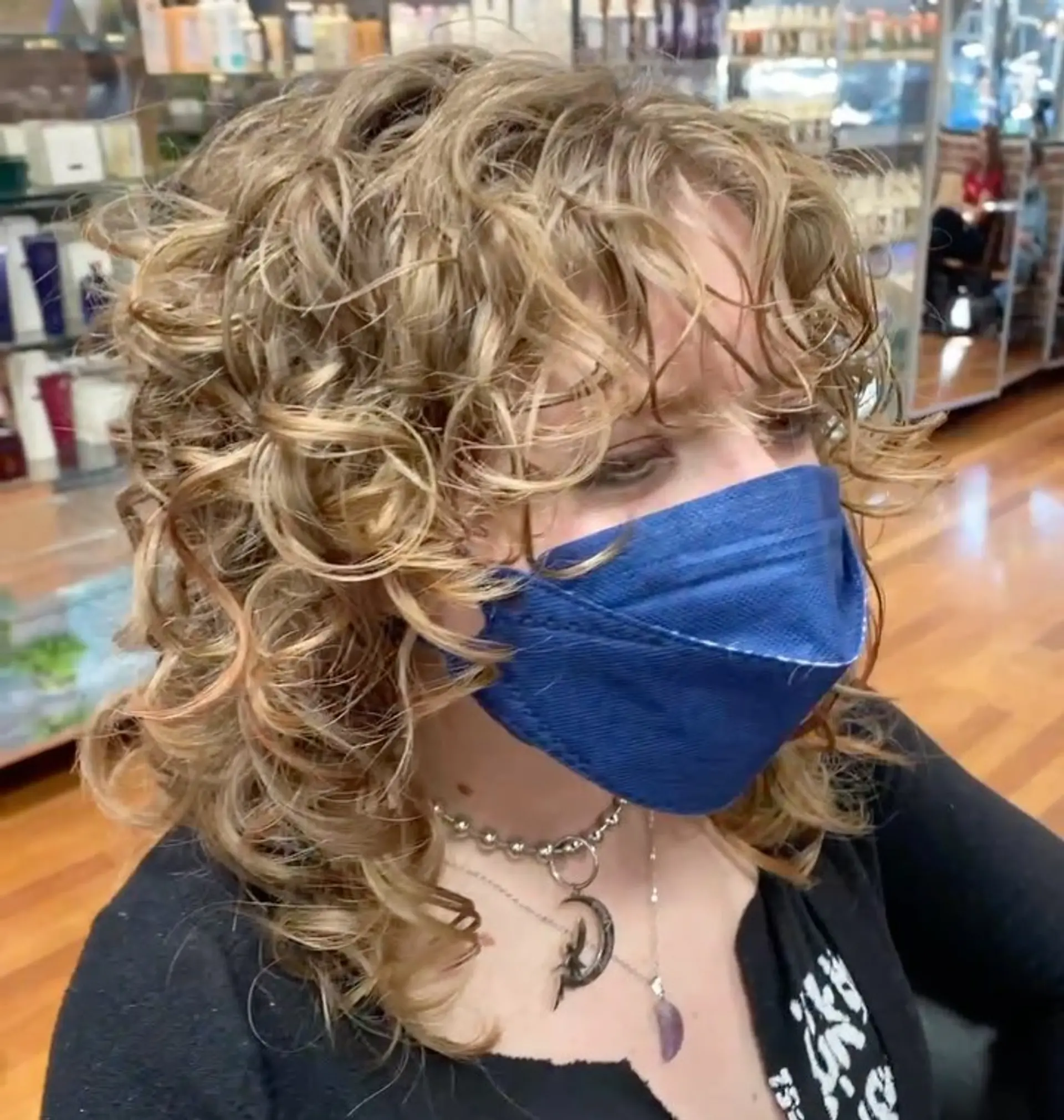 A medium-length curly shag haircut with full, diffused ringlets and curly bangs framing the face. 1