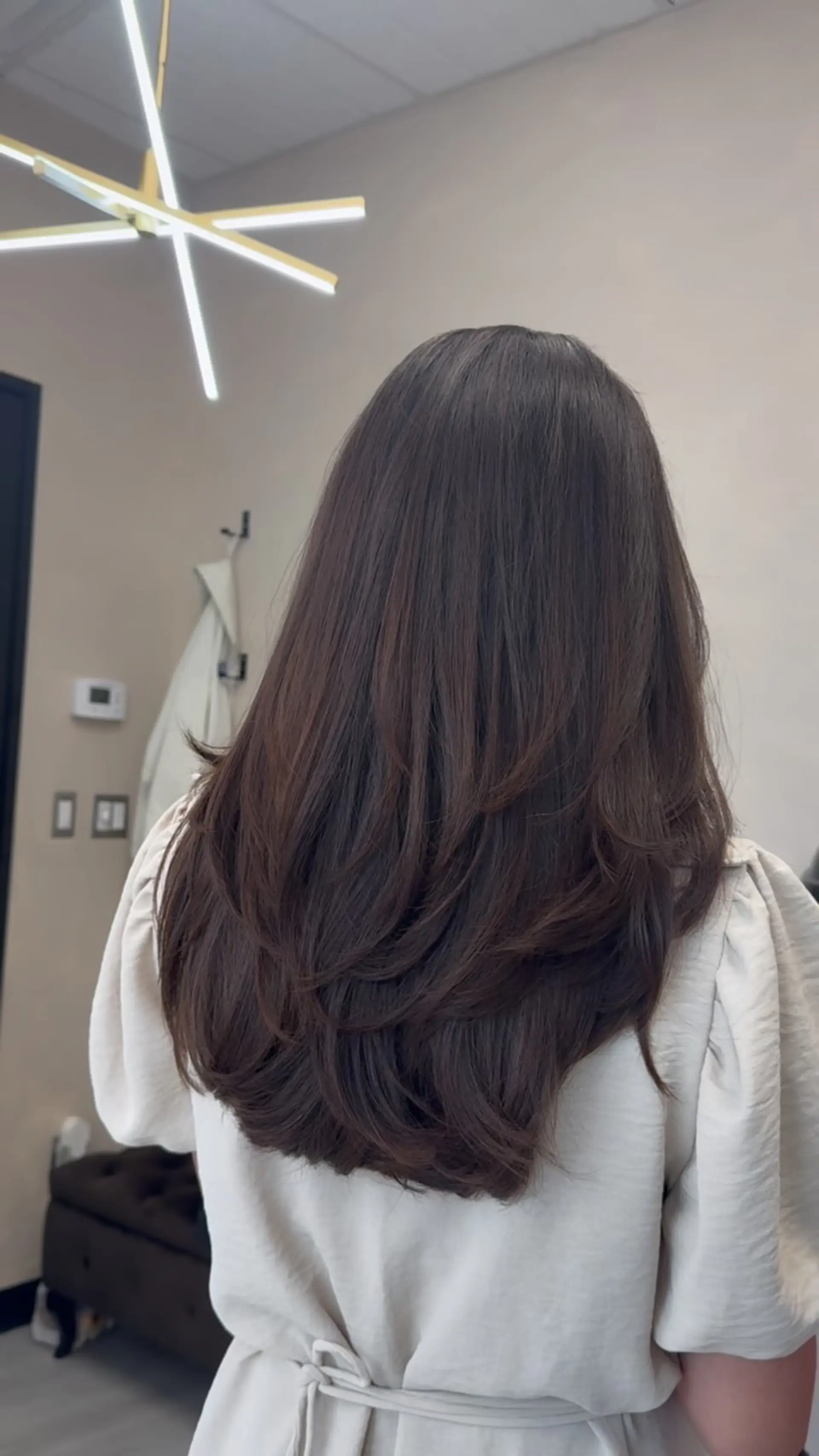Long rich dark brown hair shaped with seamless tiered layers and polished, curled-under ends for maximum bounce and movement. 1