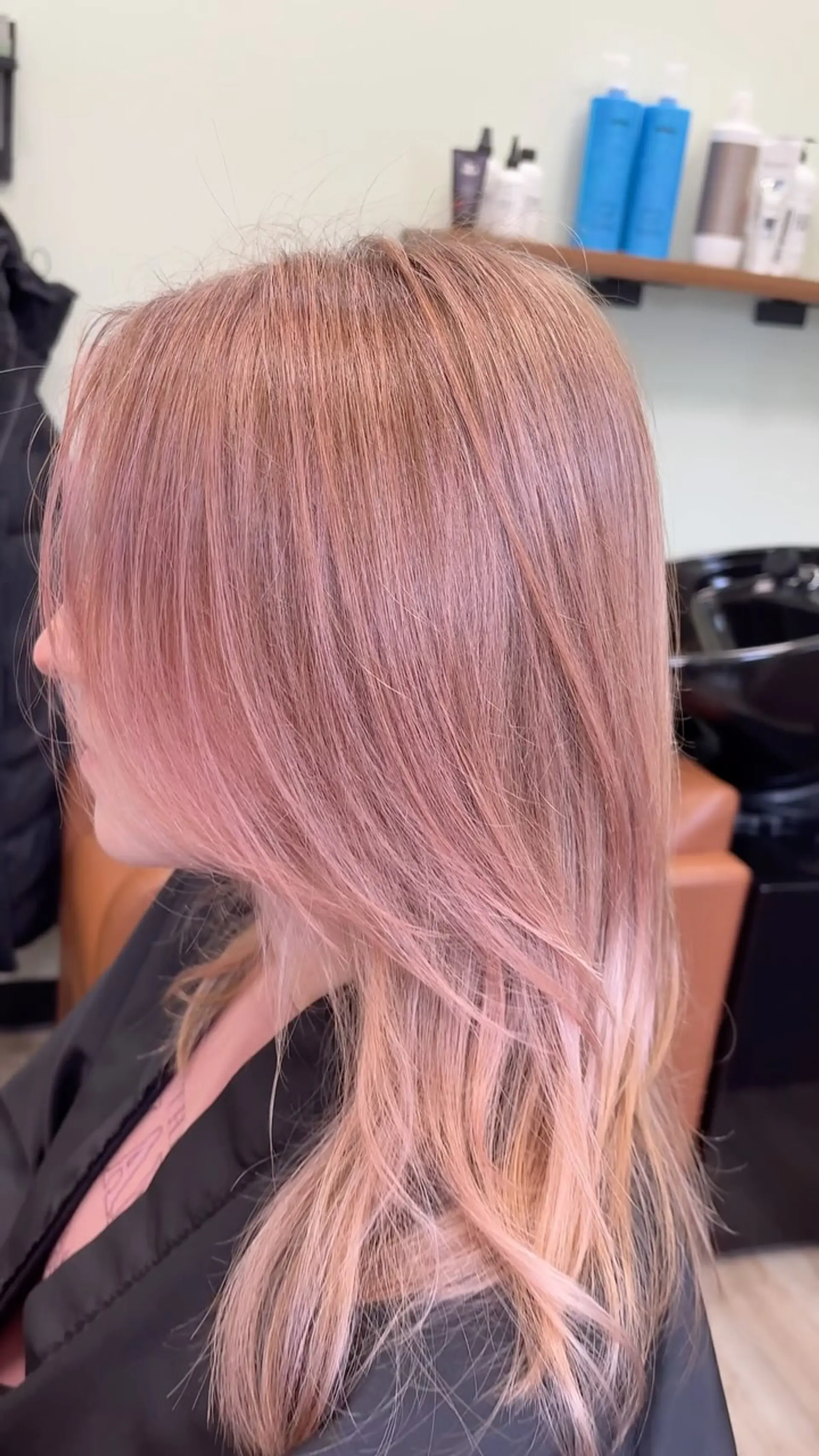 A soft pastel pink toner over lightened hair with gentle face-framing layers and smooth, straight styling. 1