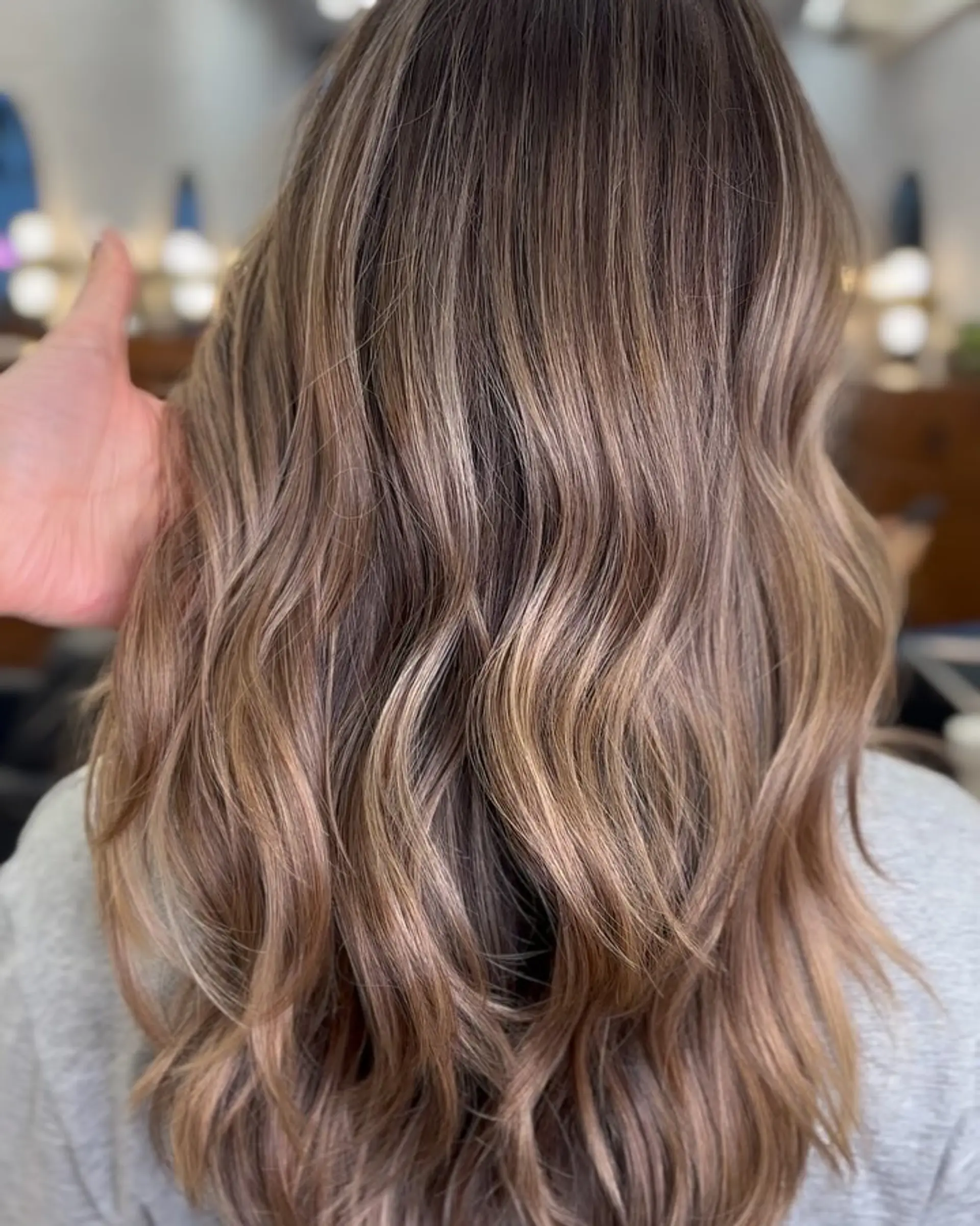 Long hair featuring a multi-tonal bronde color melt styled into soft, natural waves. 1