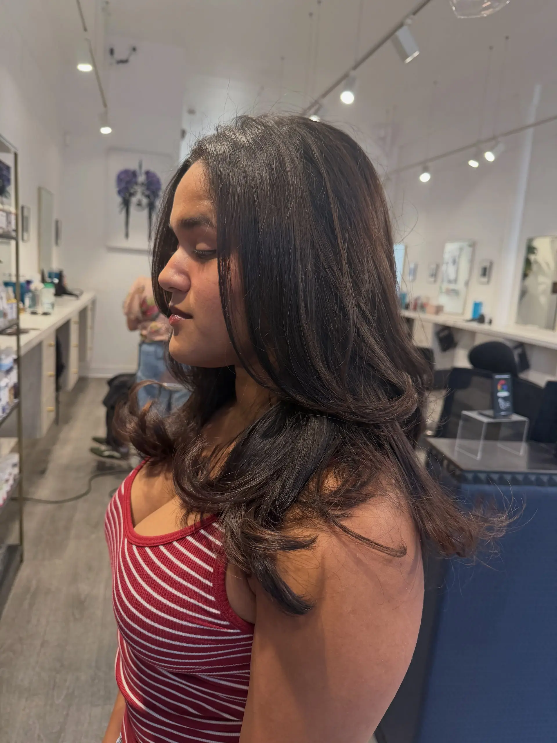 Medium-length dark brown hair cut with blended layers and styled into bouncy, soft waves. 1