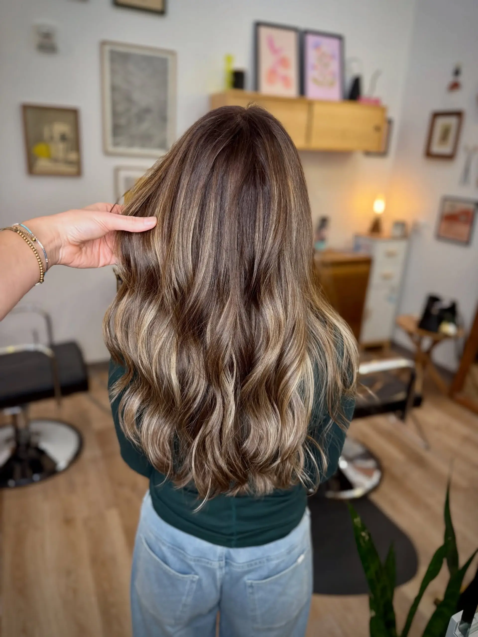 Long cascading waves featuring a dimensional blend of cool-toned ash blonde and light brown balayage over a natural brunette base. 1