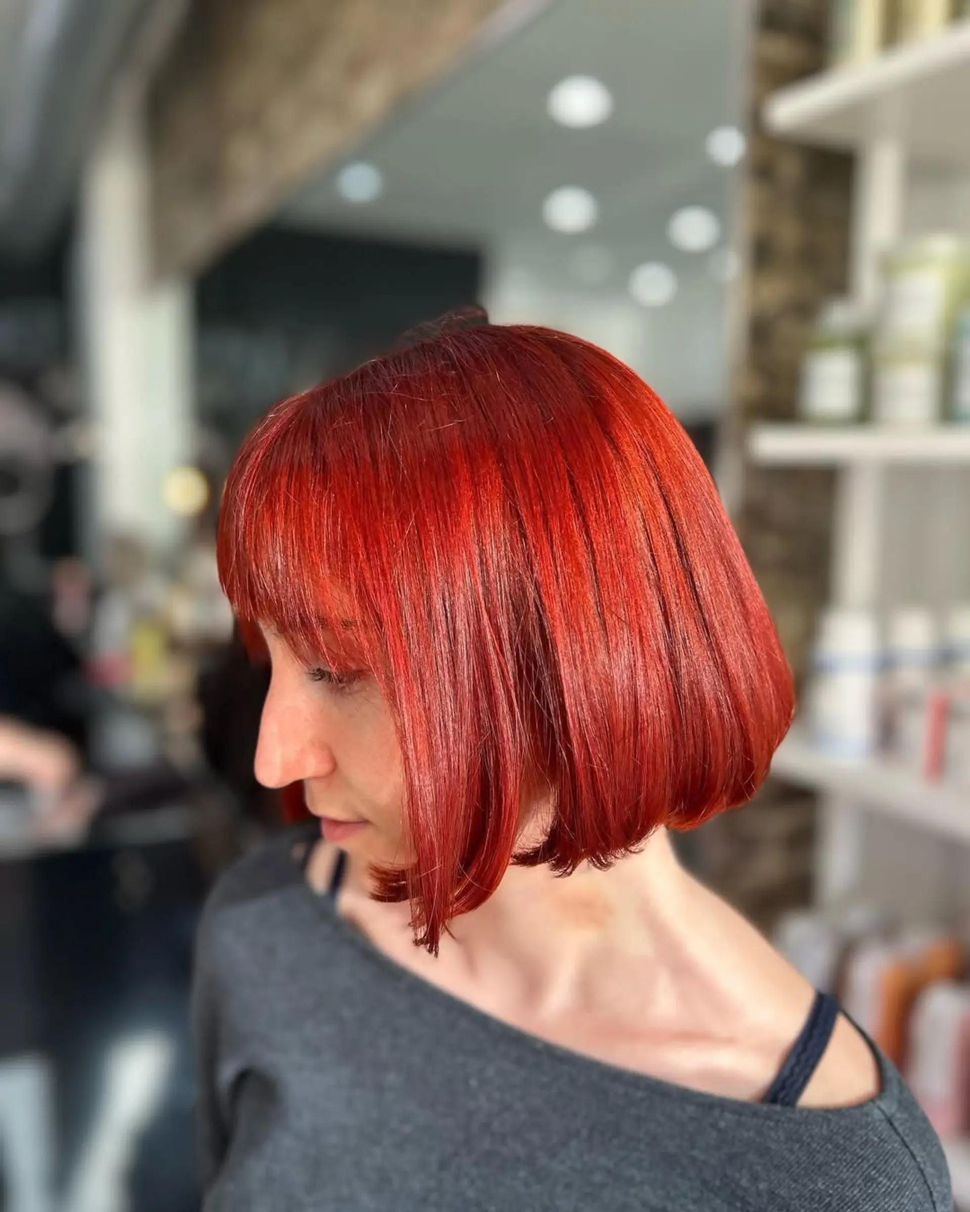 A vibrant, fiery red blunt bob with a full, straight fringe, styled sleek and chin-length. 1