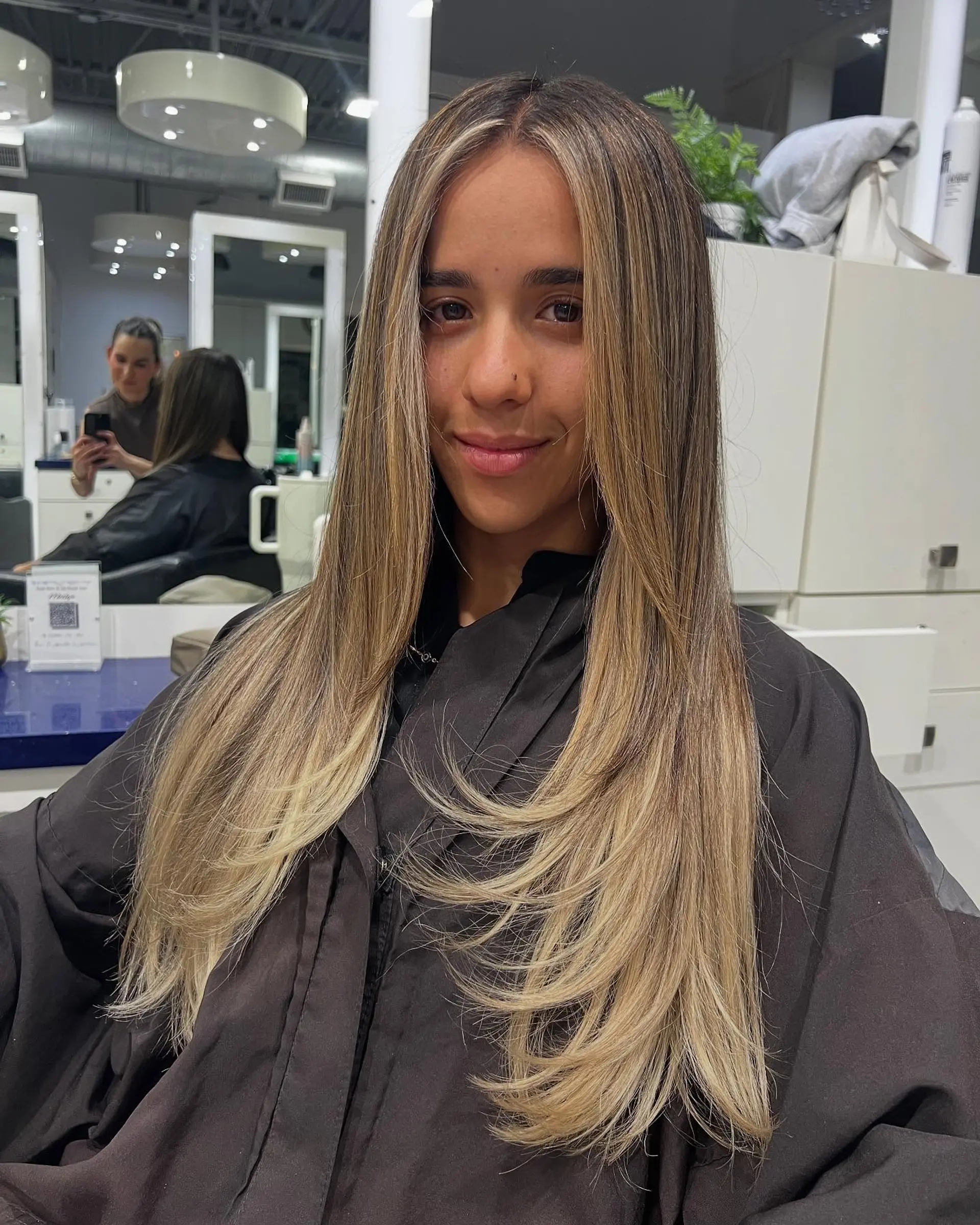 Long layered haircut with face-framing layers and a balayage color melt. 1