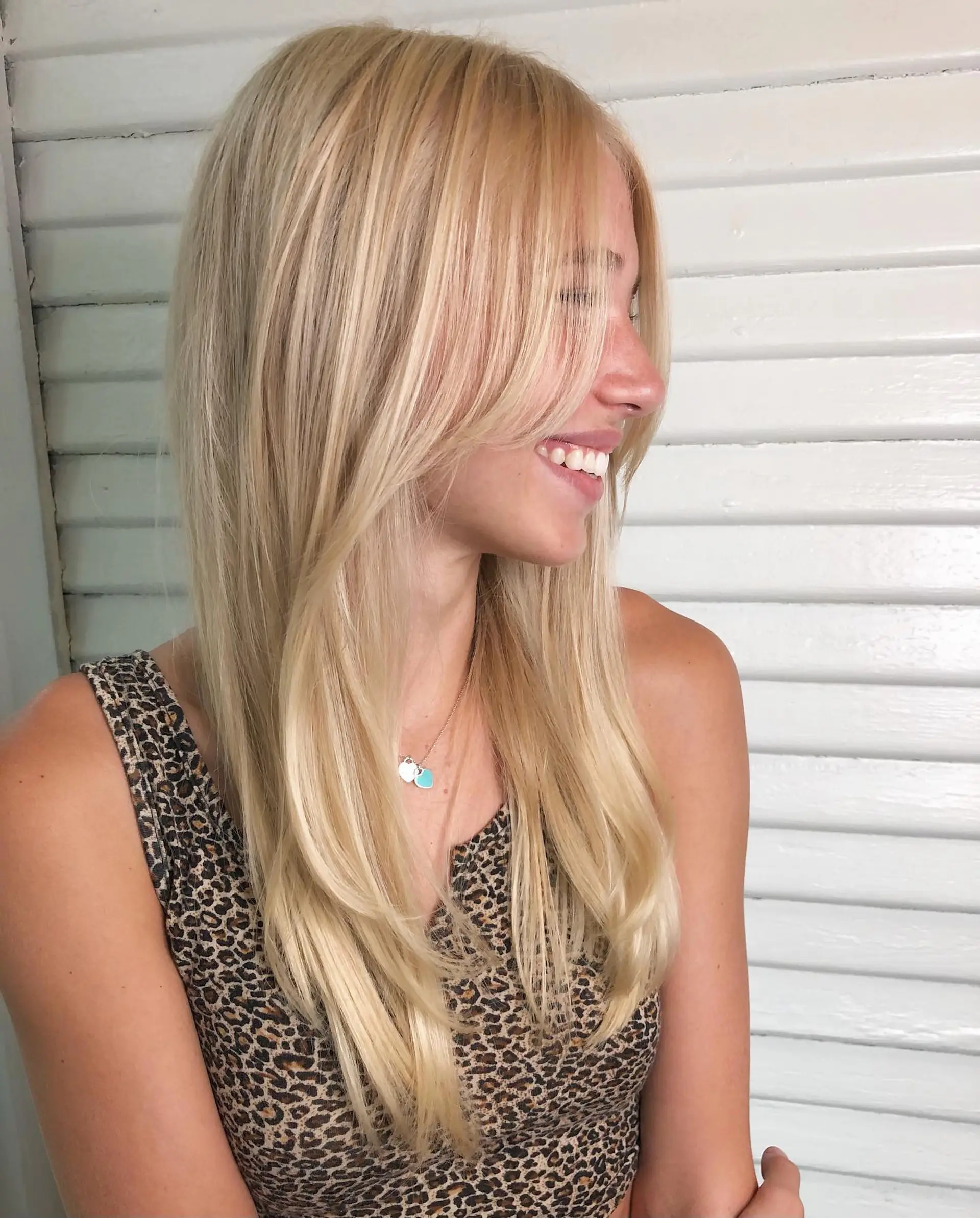 Long natural blonde hair cut with softly swept curtain bangs and subtle face-framing layers. 1