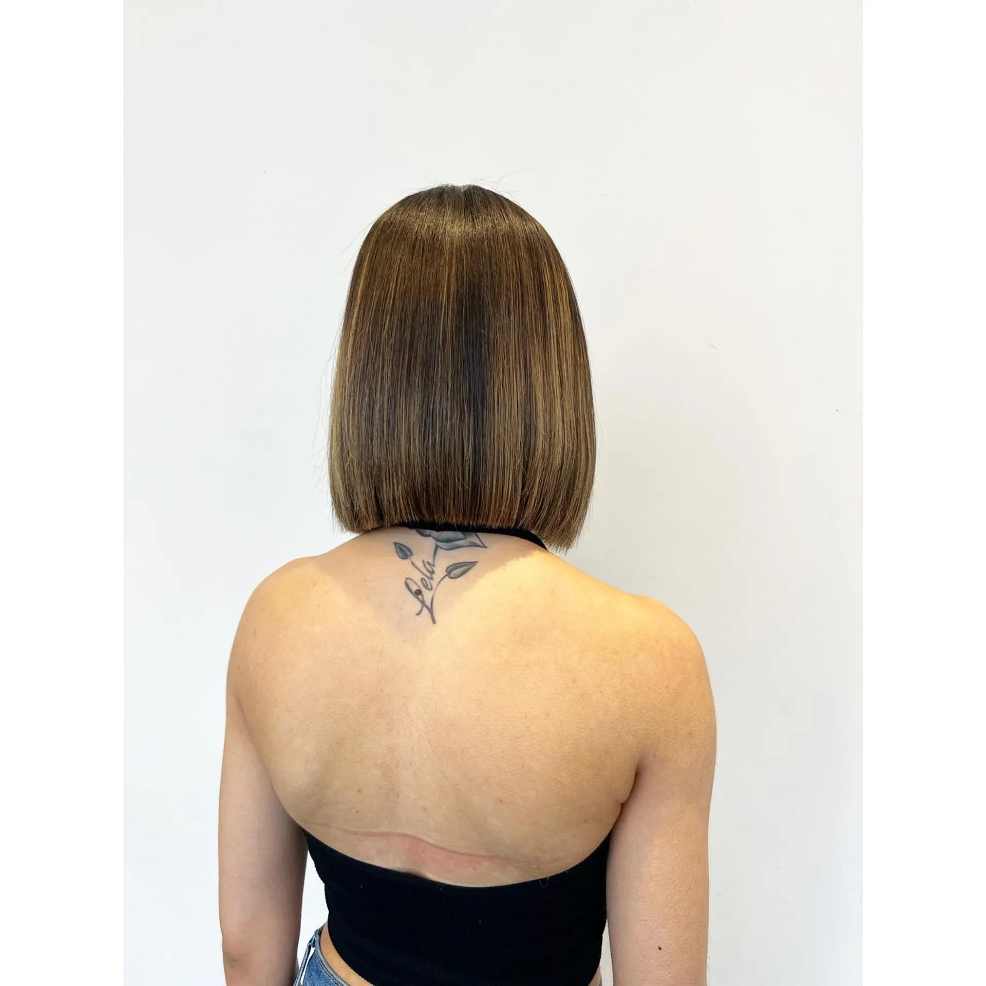 A sleek, precision blunt-cut bob styled straight with smooth ends and subtle warm dimensional highlights. 1
