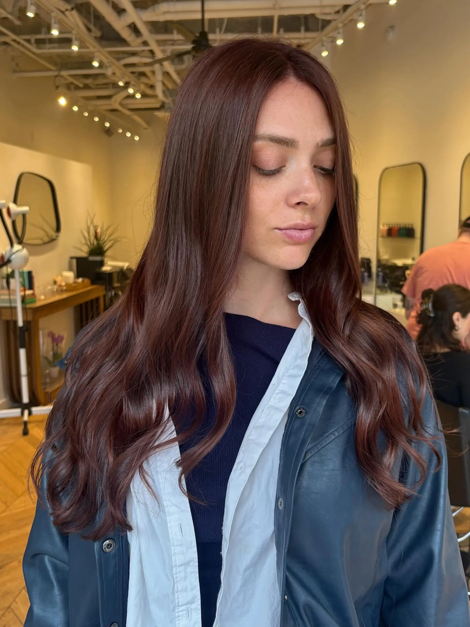 Long mahogany auburn hair styled straight at the top with gentle, loose waves at the ends. 1