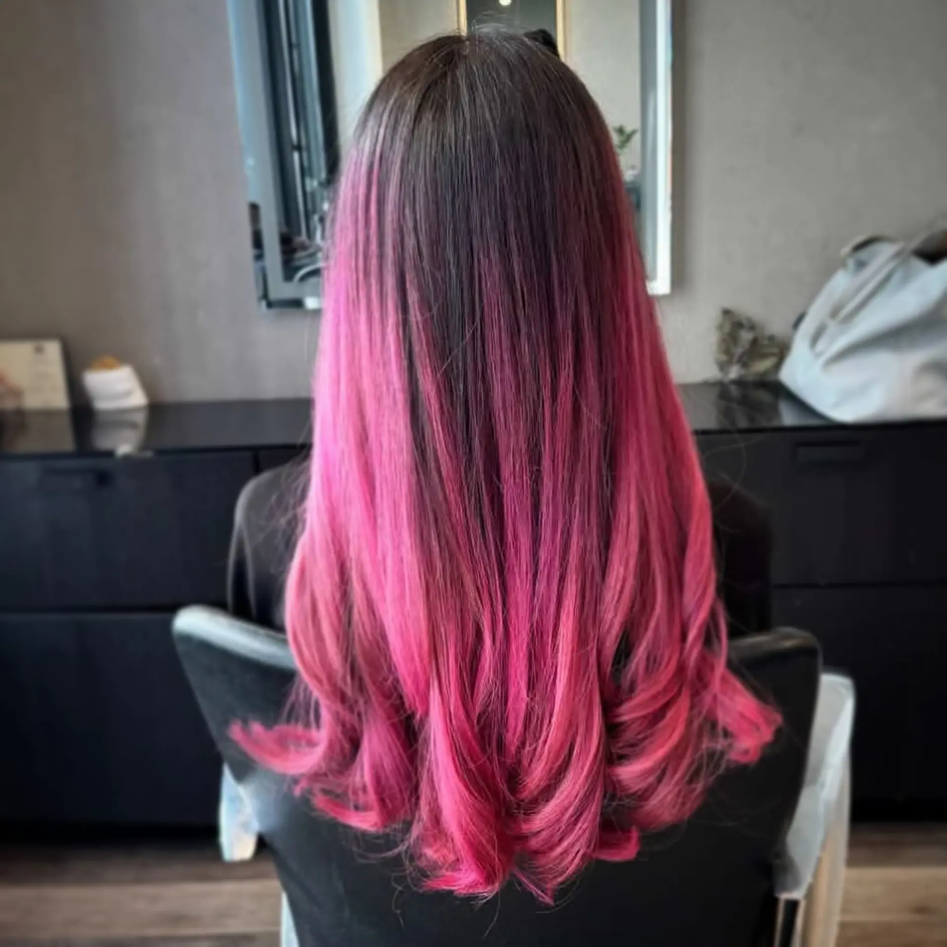 Long dark hair transitioning into a vivid hot pink ombre, finished with soft flipped-under curls at the ends. 1