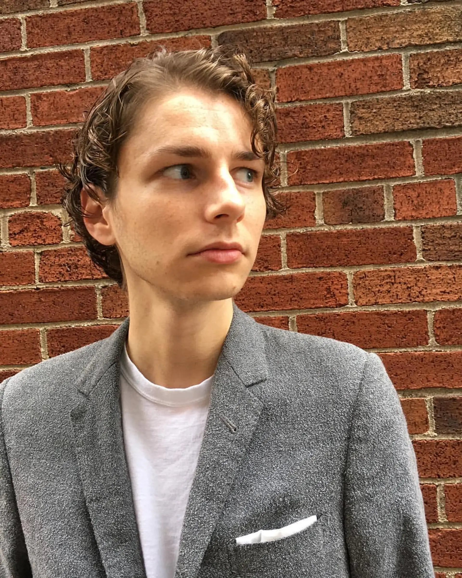 Short, light brown wavy hair with a slightly wet look, softly defined waves, and a neat, layered structure, giving a relaxed yet stylish appearance. 2