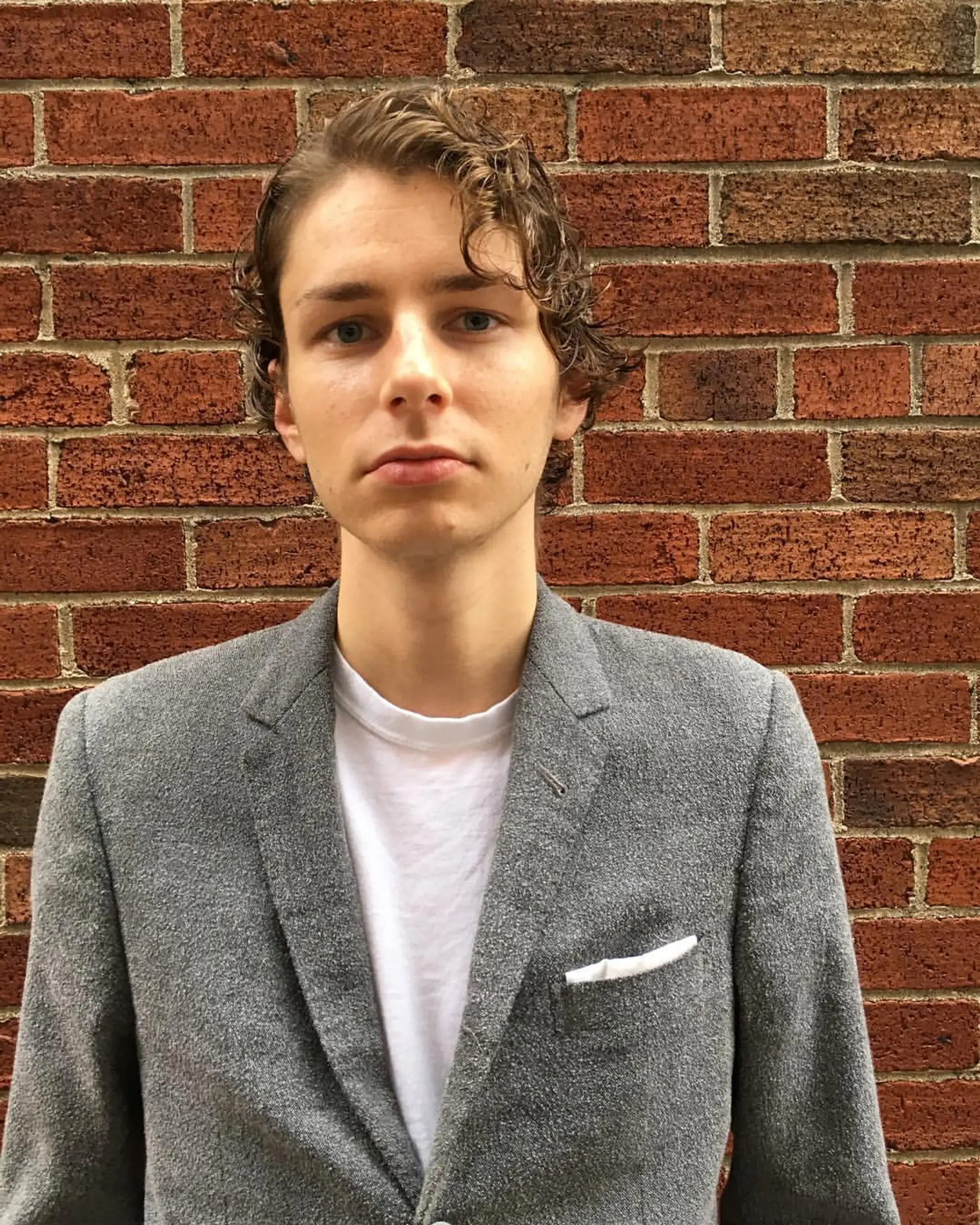 Short, light brown wavy hair with a slightly wet look, softly defined waves, and a neat, layered structure, giving a relaxed yet stylish appearance. 3