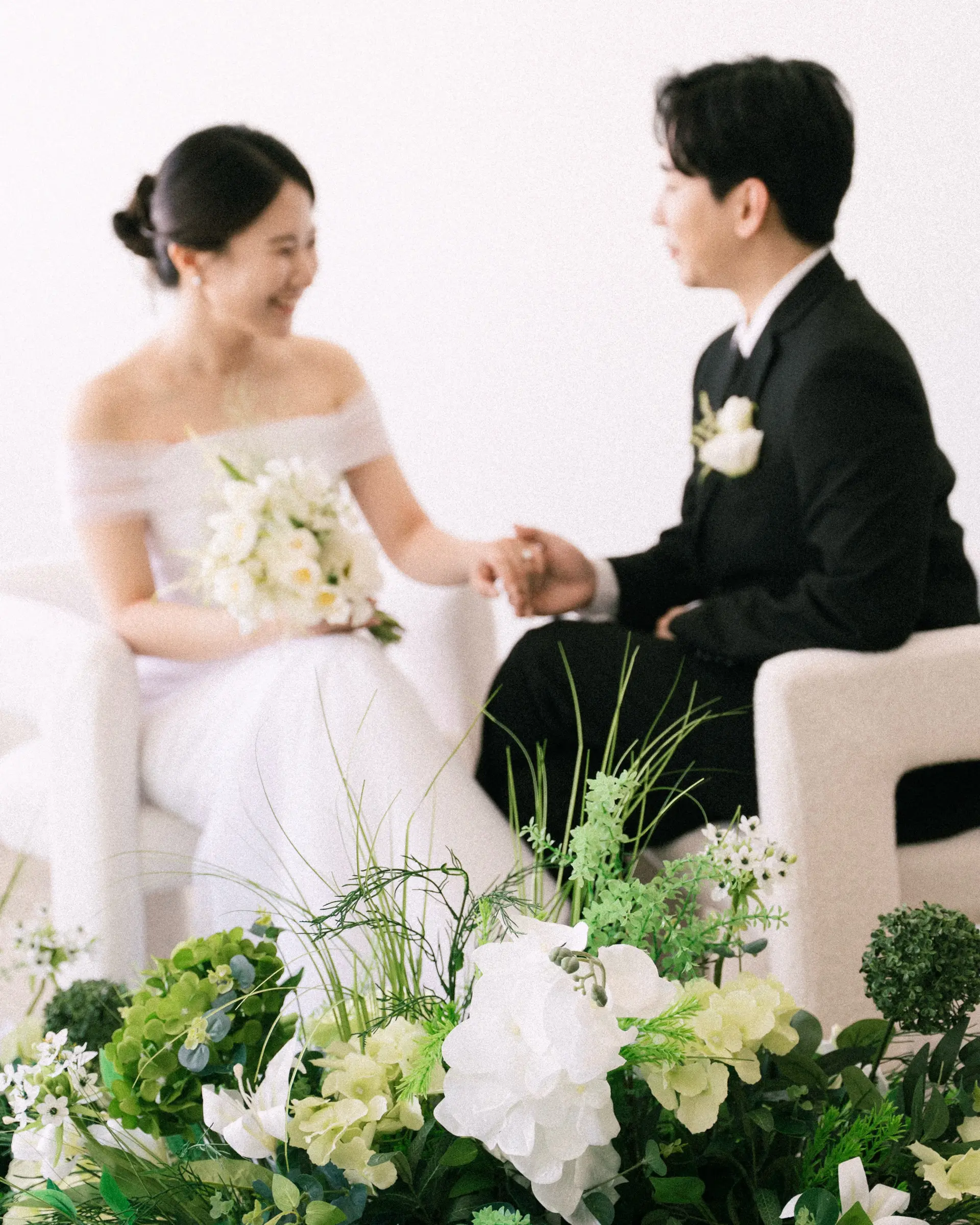 An elegant bridal low bun updo complemented by classic groom styling for a studio photo session. 1