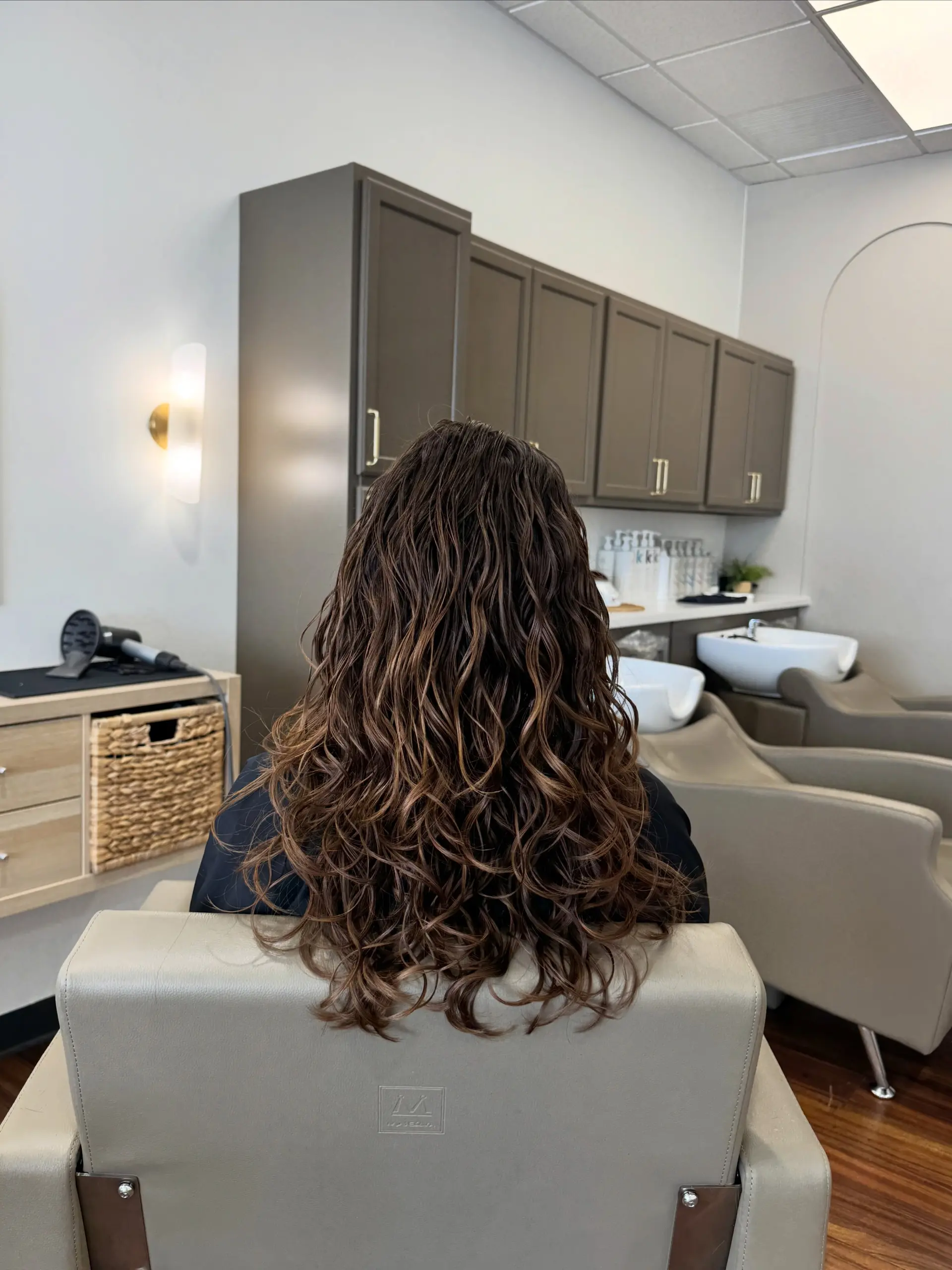 Long brown hair styled with defined, bouncy curls showcasing natural texture and movement. 1