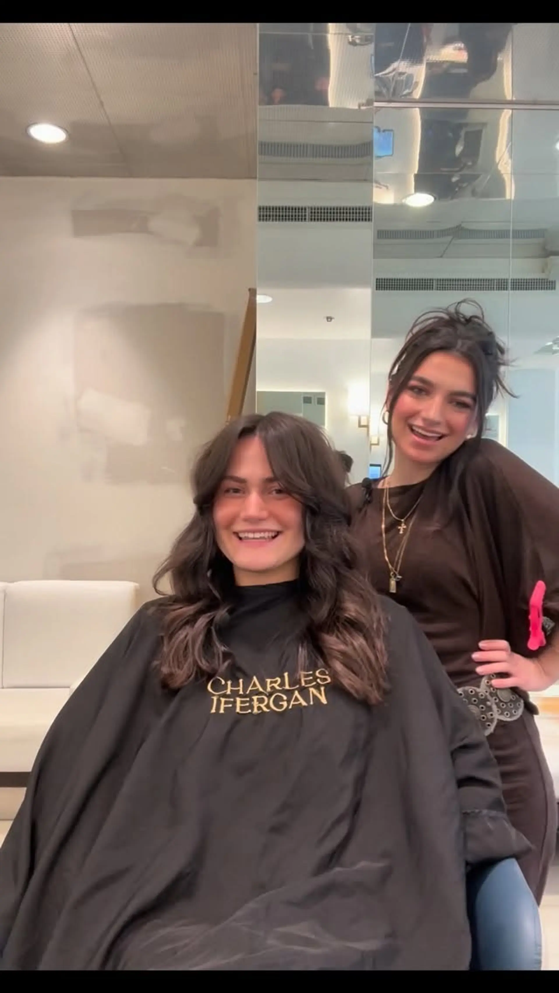 Medium-length dark brunette hair cut with soft face-framing layers and curtain bangs, styled into voluminous, loose waves. 1
