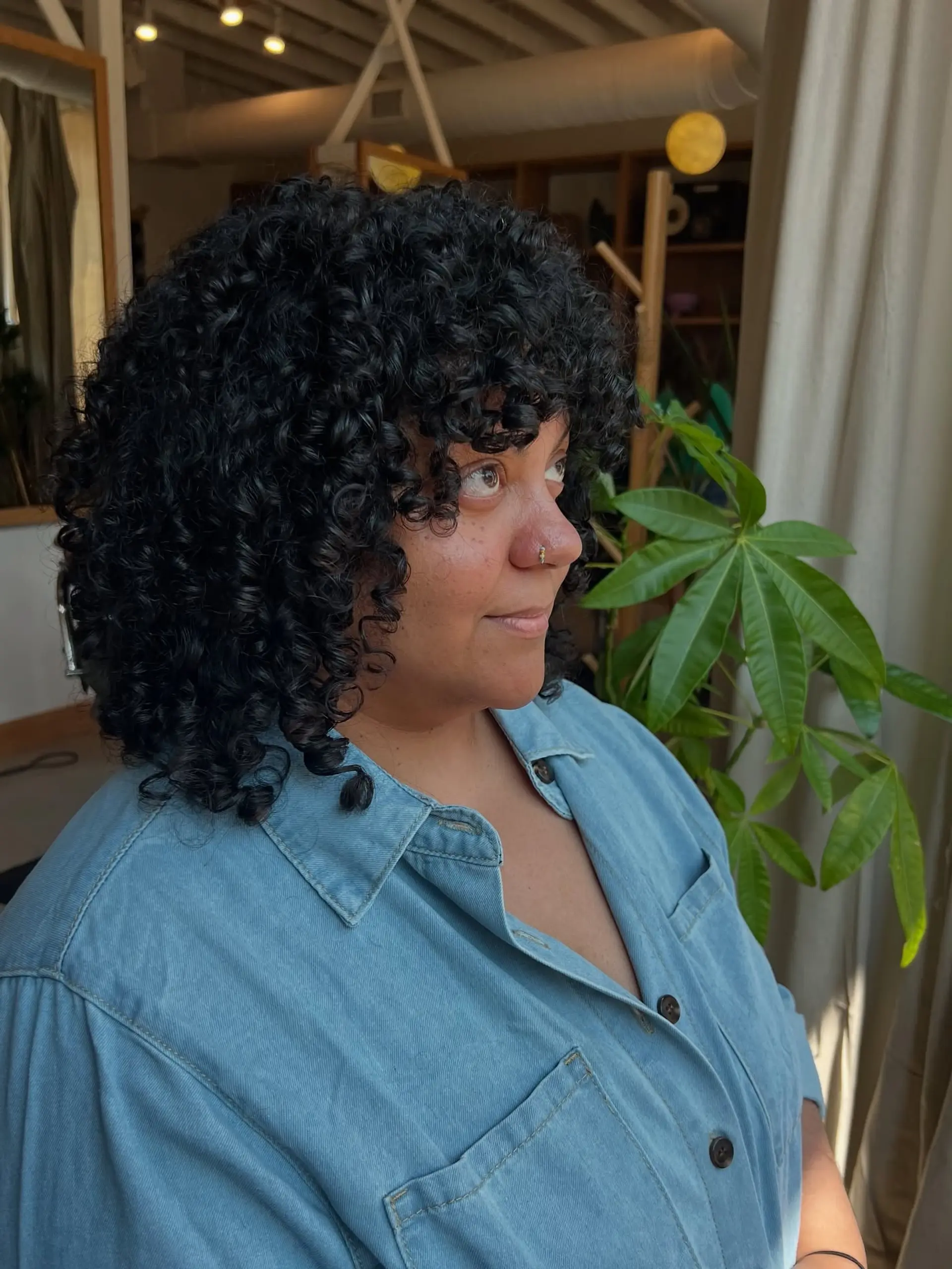 A stylish, medium-length bob haircut designed for naturally curly hair, complete with flattering bangs. 1