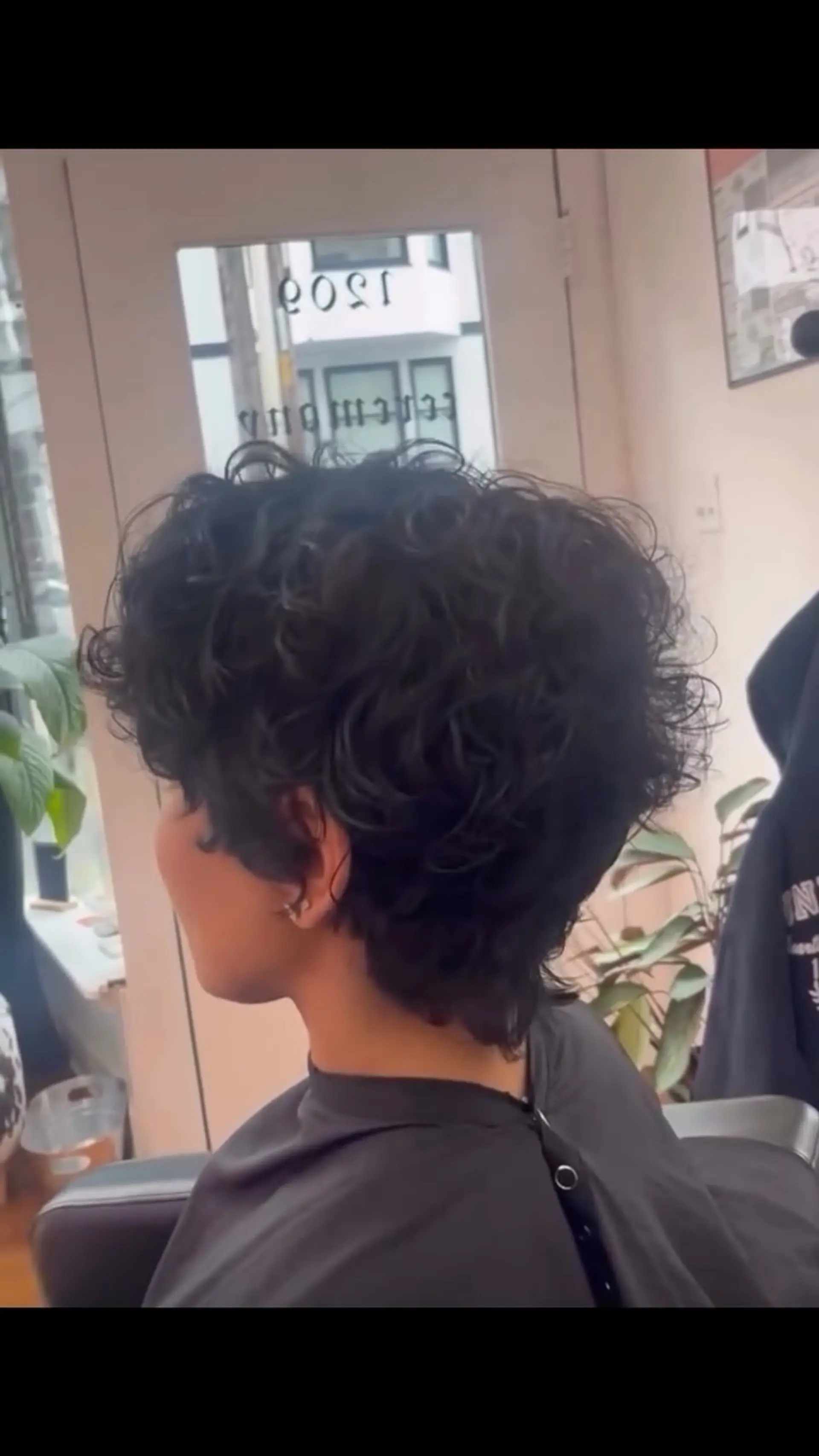 A short, voluminous curly bixie cut with textured layers tapered neatly at the nape. 1