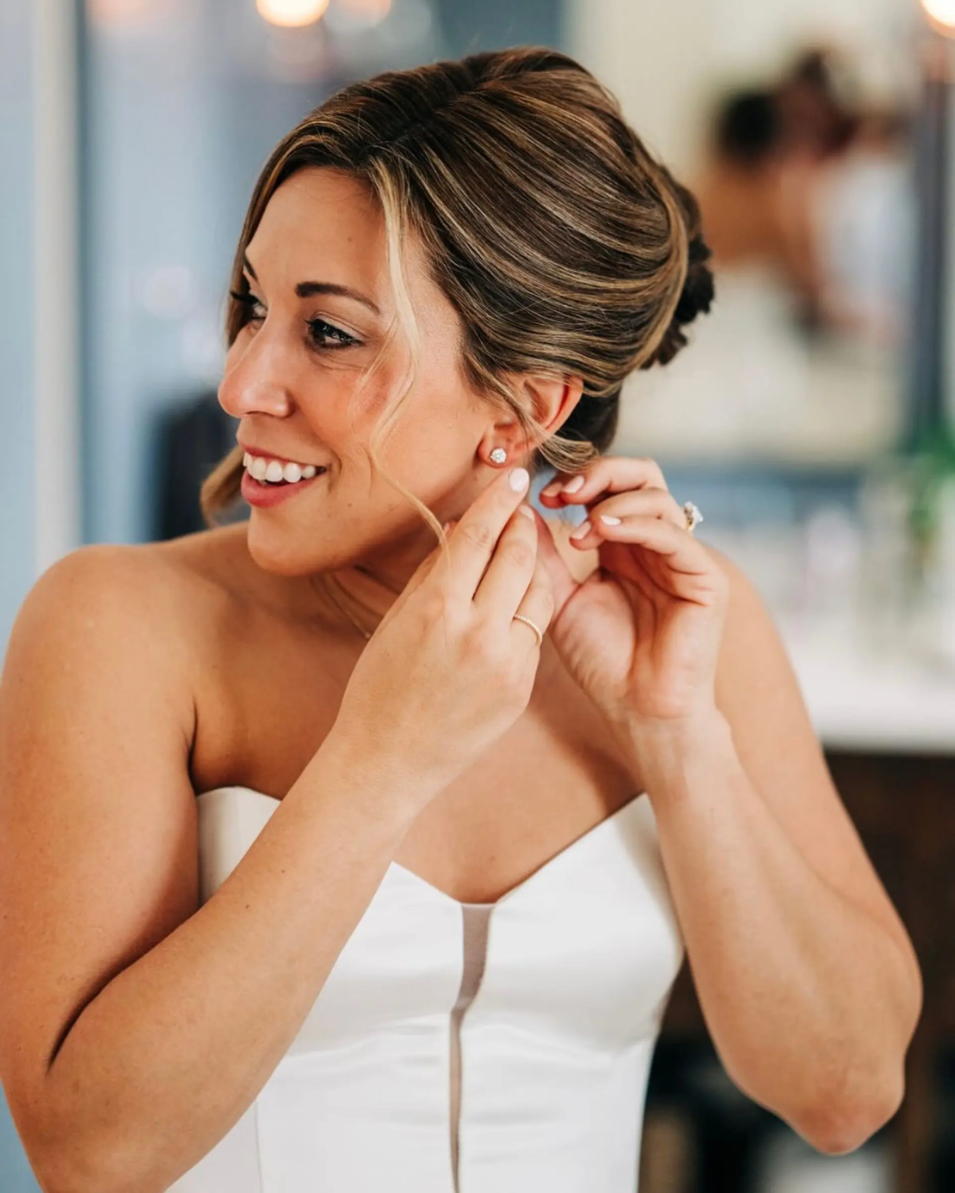 A sophisticated bridal updo styled with textured volume and soft face-framing strands. 1