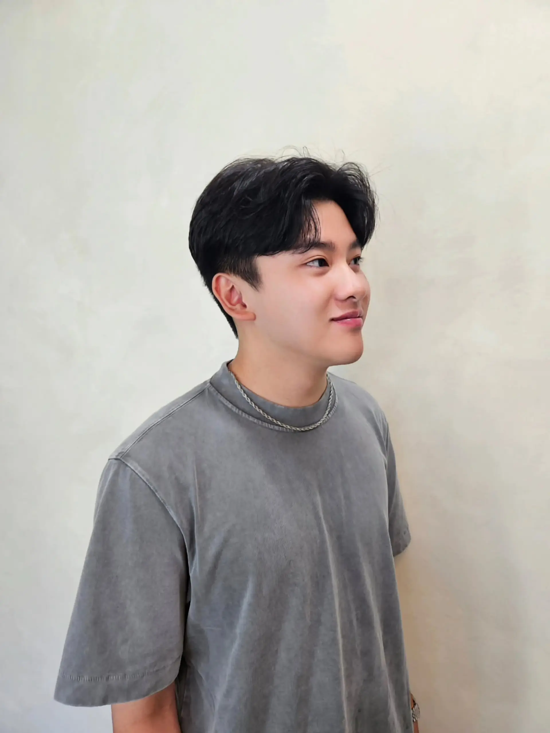 A short men's haircut styled with a soft texture perm and parted curtain bangs. 1
