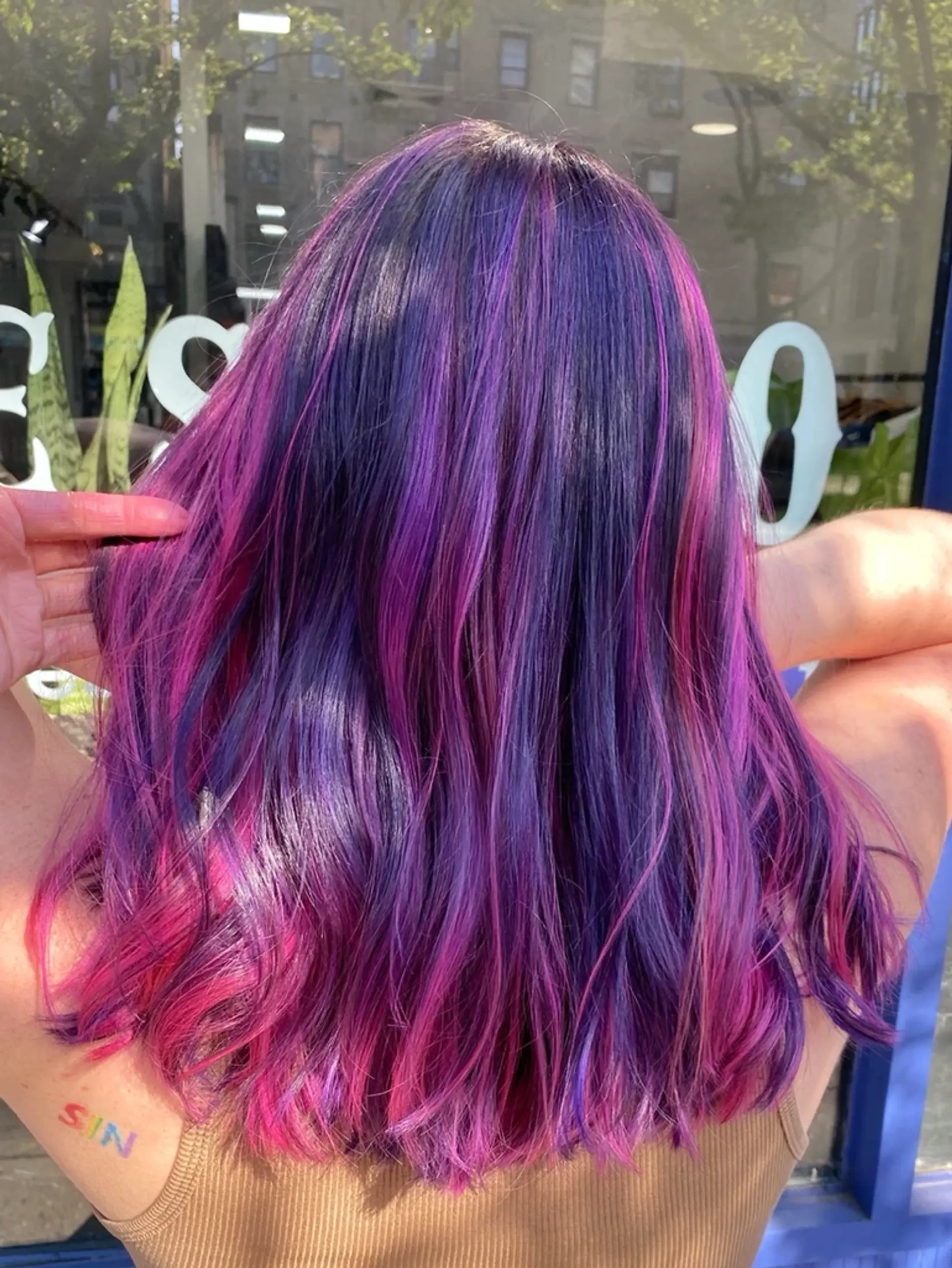 Wavy, medium-length hair with vibrant purple and pink balayage, creating an energetic and bold look. 1