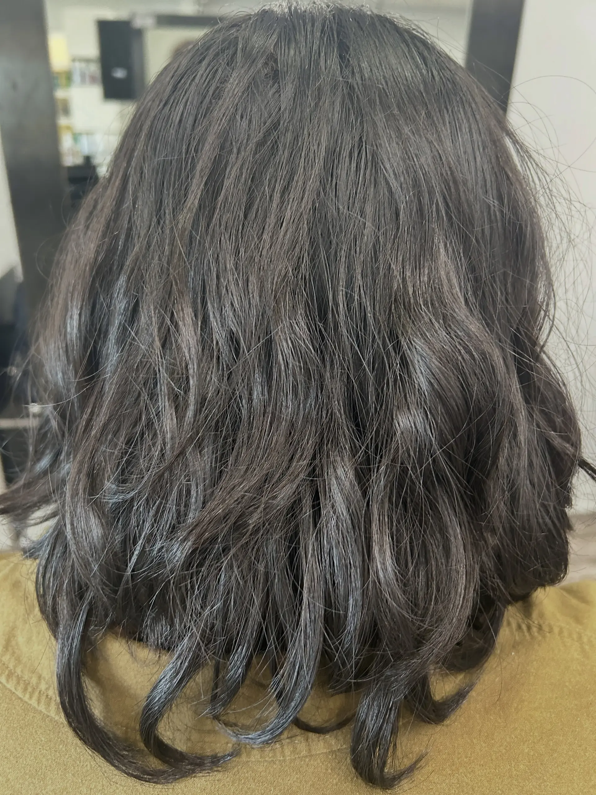 A shoulder-length textured haircut styled with loose, natural waves in a rich dark brown tone. 1