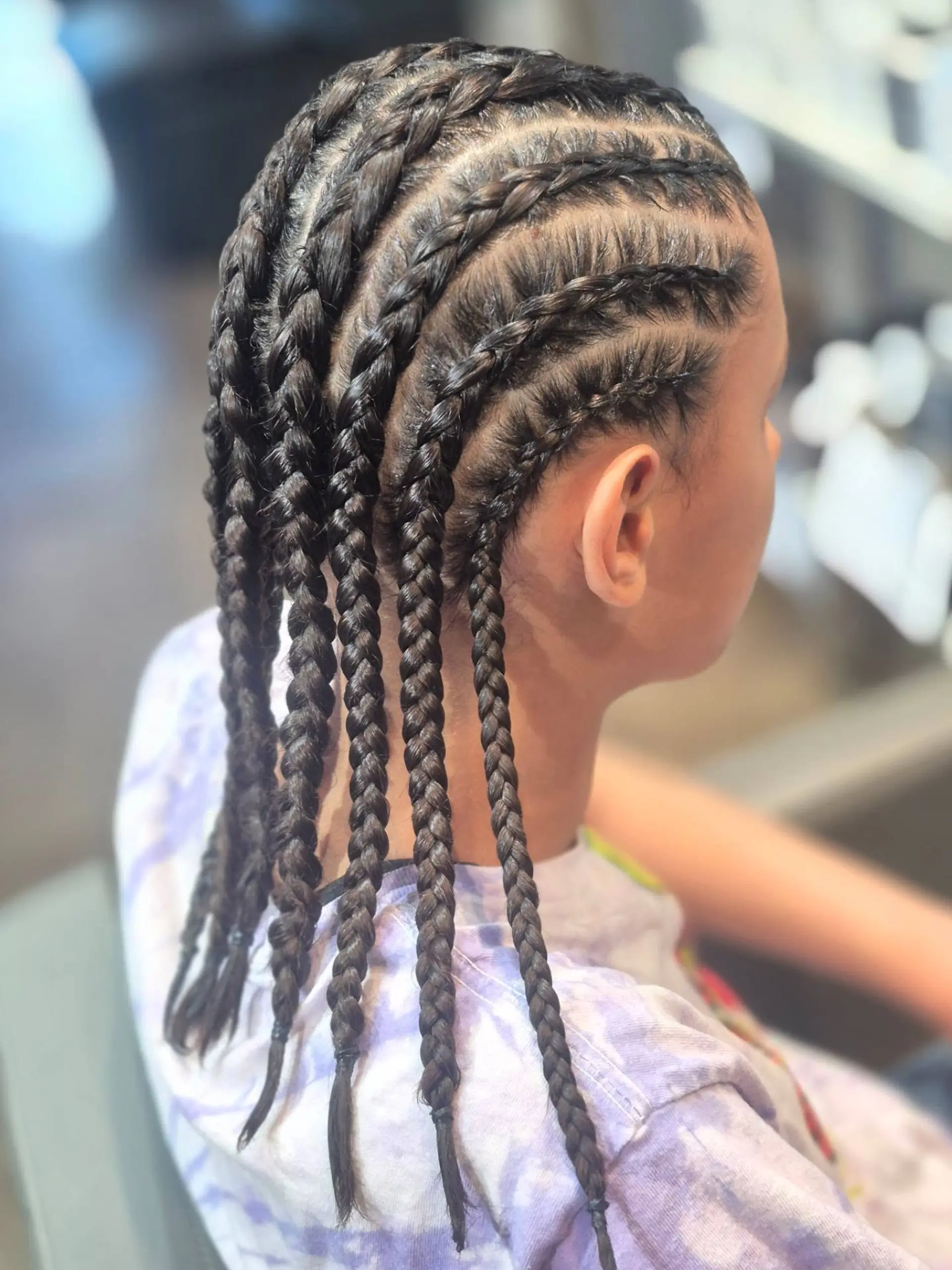 Clean, evenly parted straight-back cornrow braids extending from the front hairline down to the nape and finishing into individual hanging braids. 1