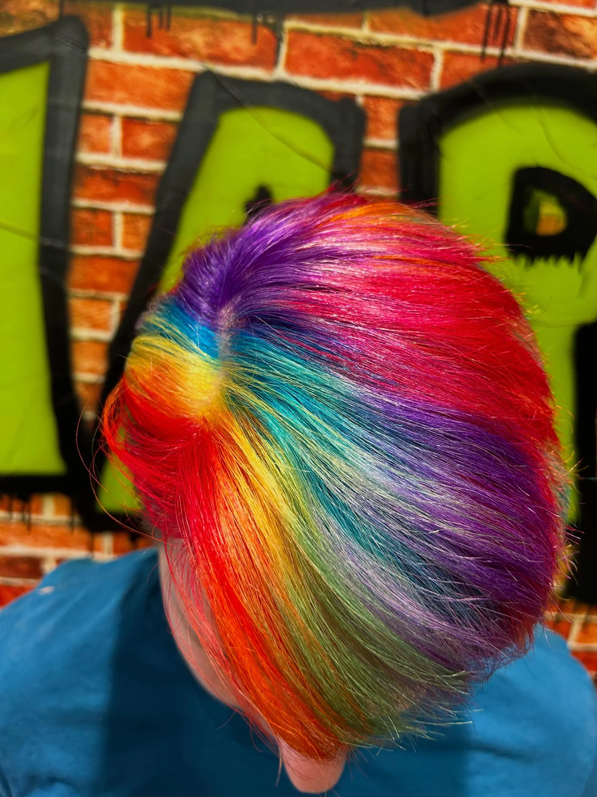 A striking multi-color rainbow hair dye on short hair featuring vivid spectrum bands from red to deep violet. 1