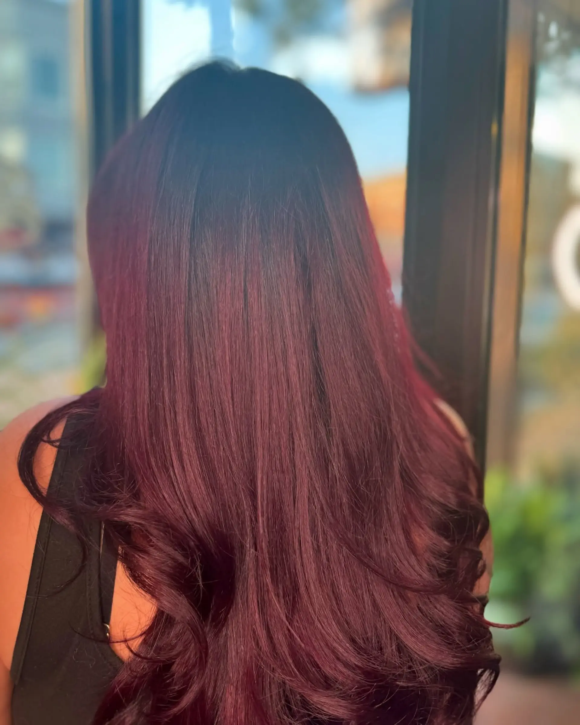 Long, vibrant mahogany hair styled smooth and sleek with soft curled ends. 1