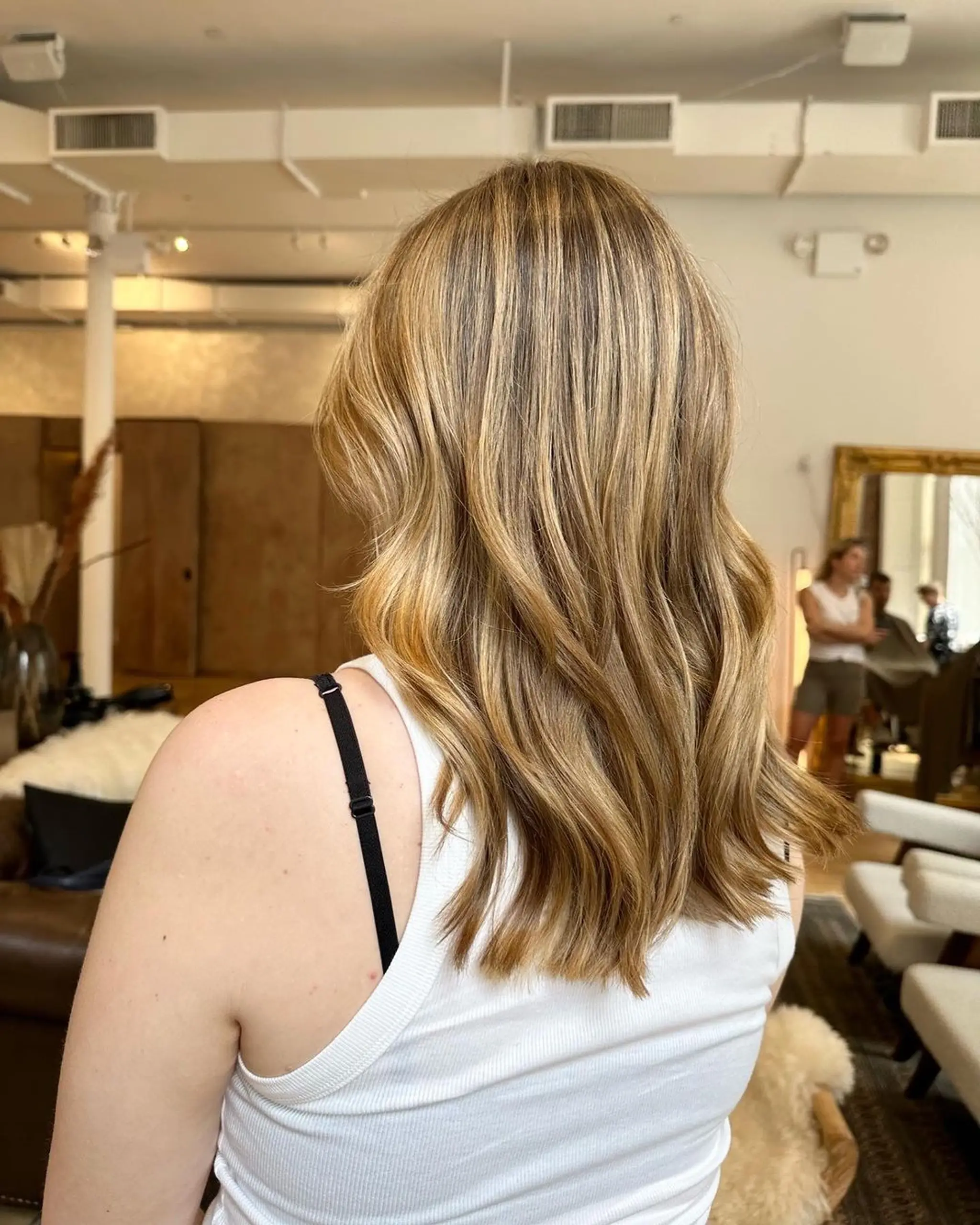 Medium-length wavy hair with golden blonde, honey, and brown shades, creating a natural, beachy look.