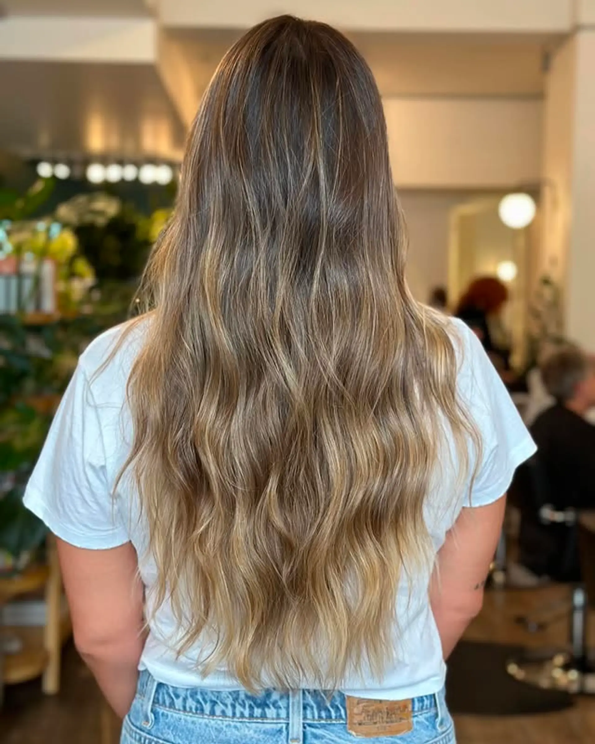Long, layered hair with a bronde balayage creating a dimensional, wavy look. 1