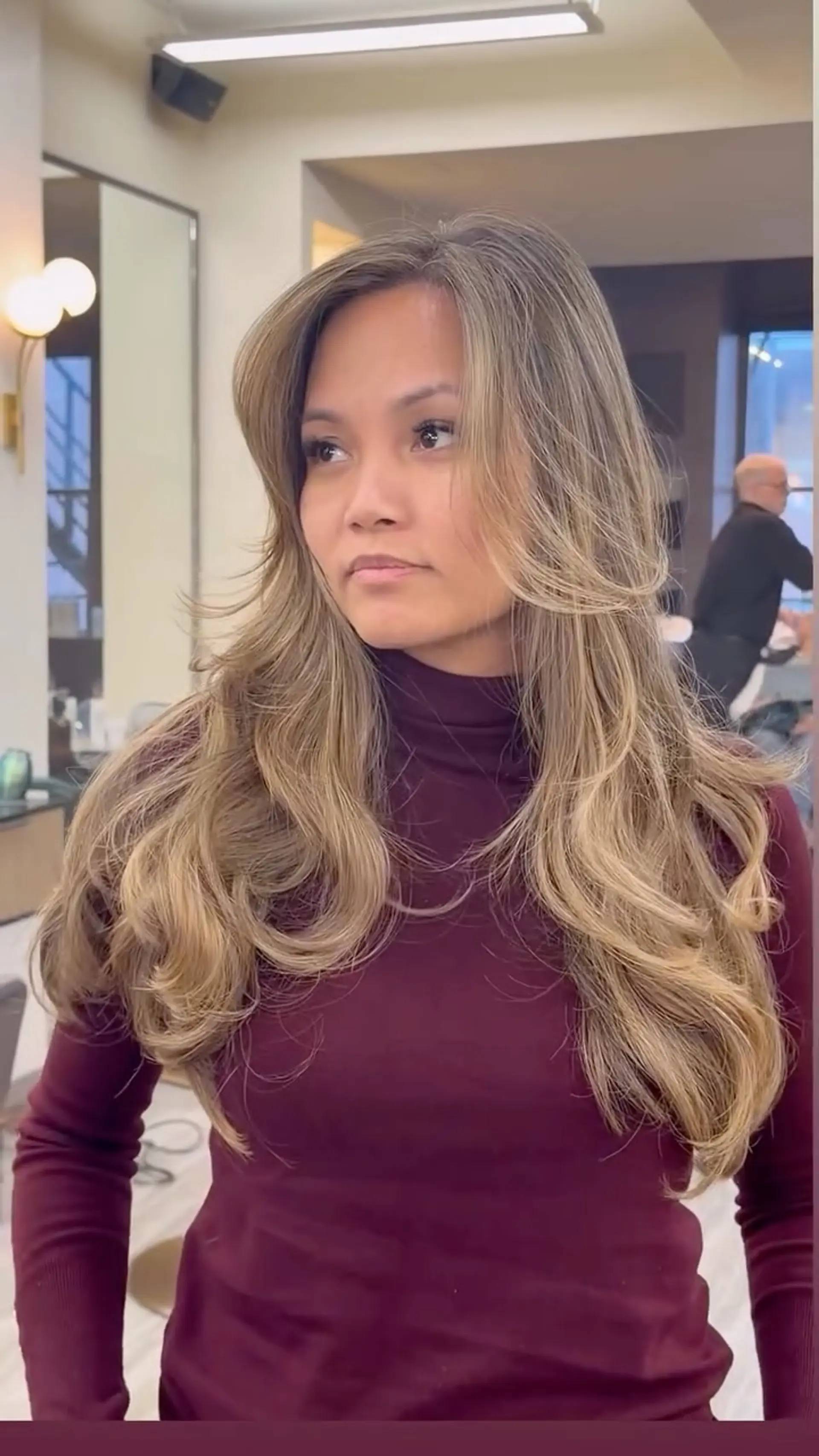 Long sandy blonde hair styled with voluminous face-framing layers and soft bouncy curled ends. 1