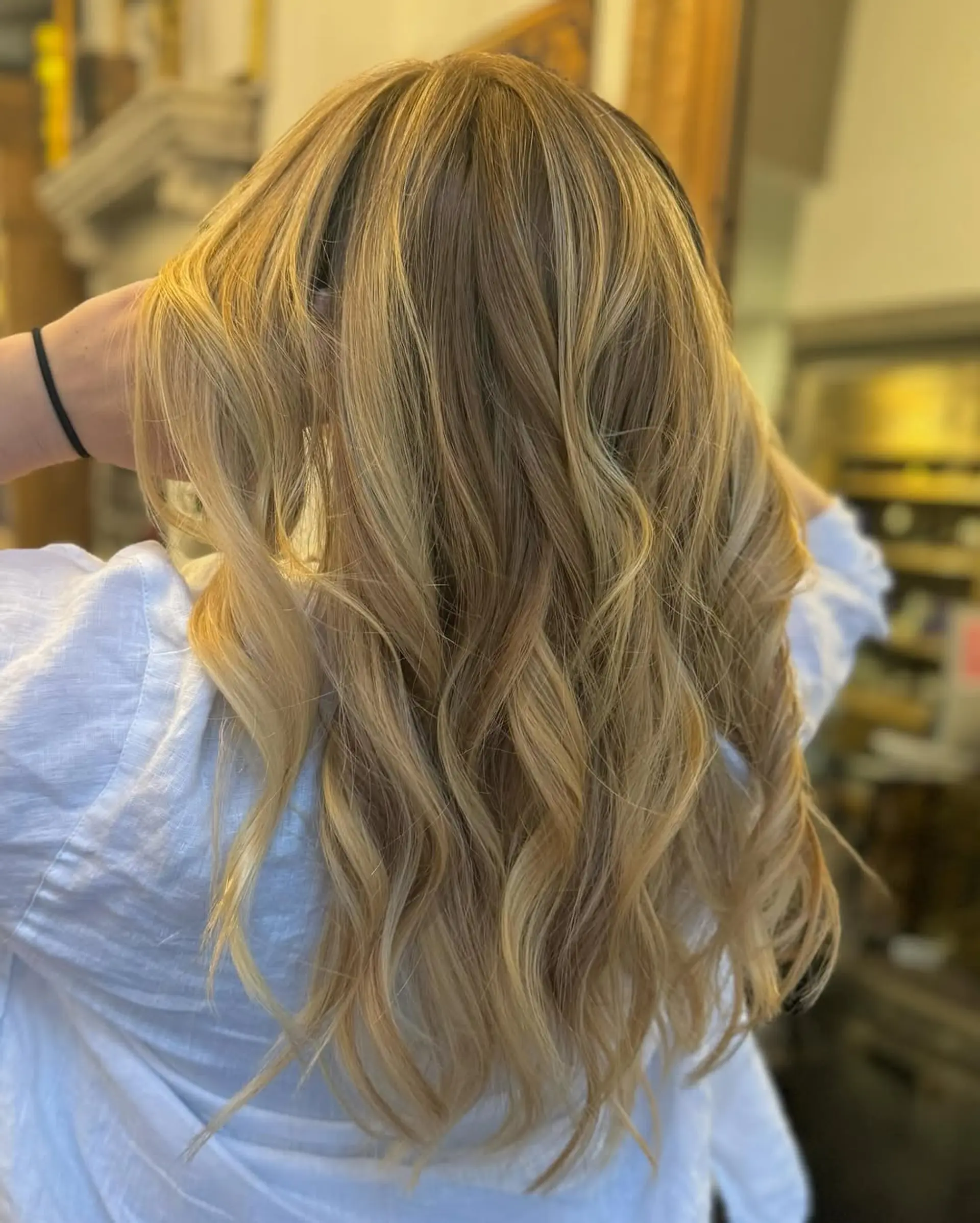 Luxurious long hair with wavy texture, featuring blonde, honey, and caramel shades in a balayage style. The natural highlights and layered ends add softness and movement. 2