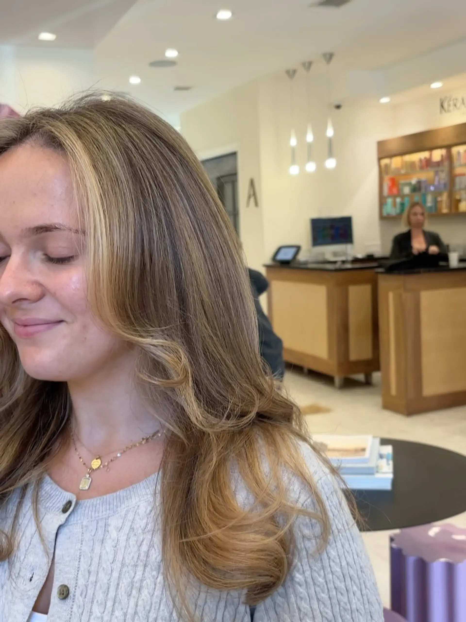 Dimensional rich bronde color featuring soft warm highlights and a bright, face-framing money piece styled in smooth waves. 1