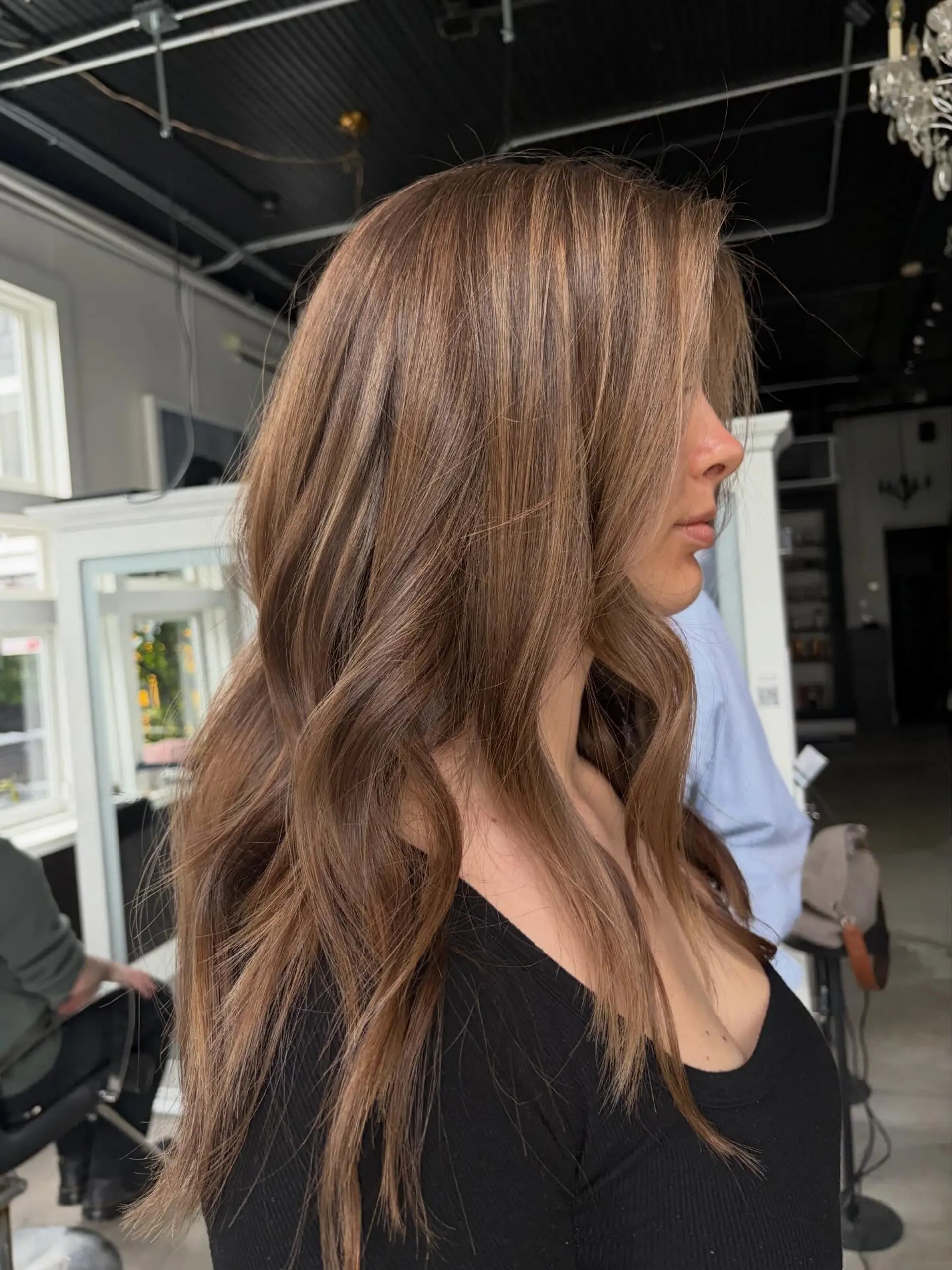 Long dimensional bronde hair styled with soft, cascading waves and subtle face-framing layers. 1