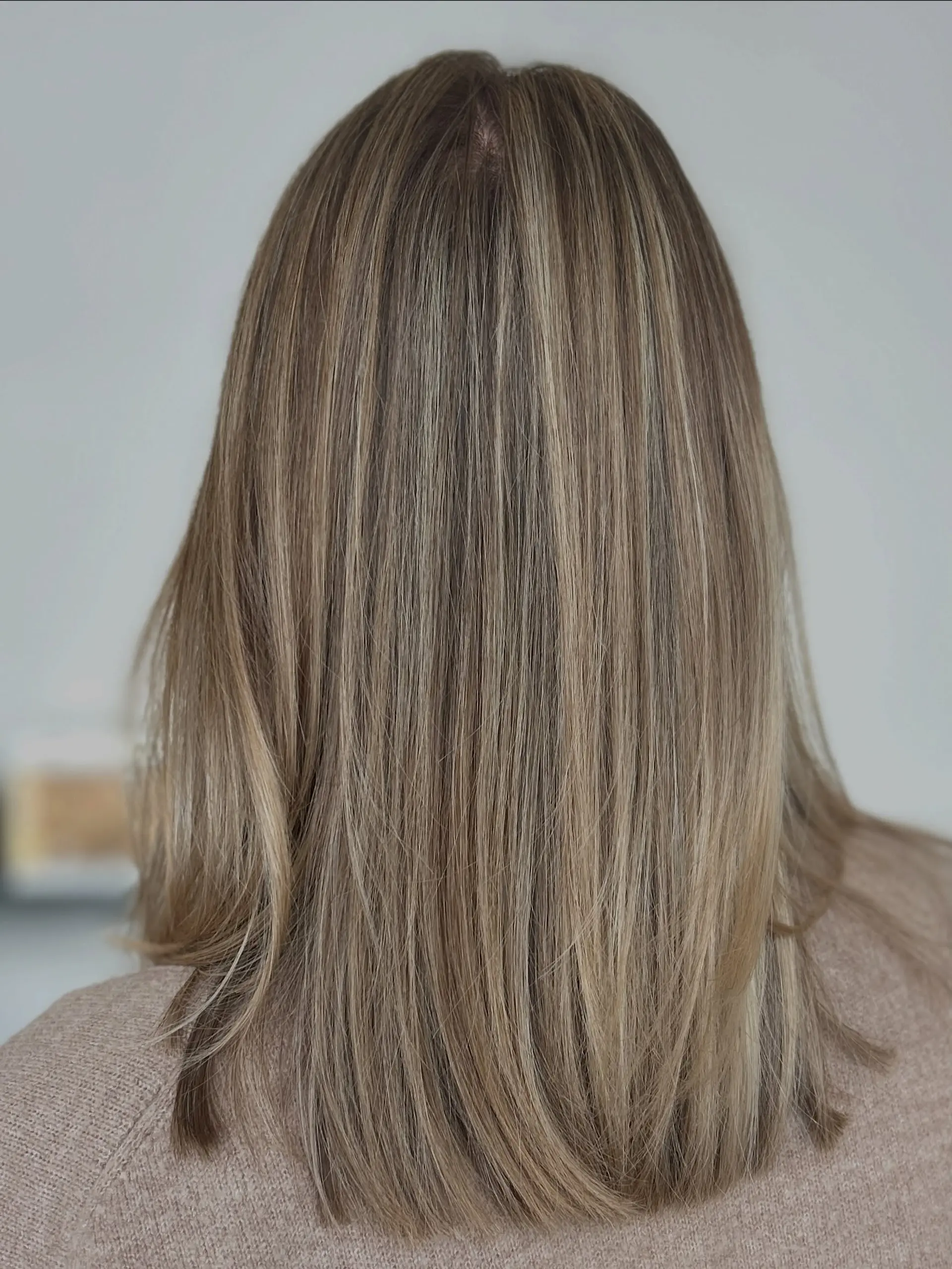 Straight medium-length light brown hair styled with fine, dimensional ash blonde highlights throughout. 1