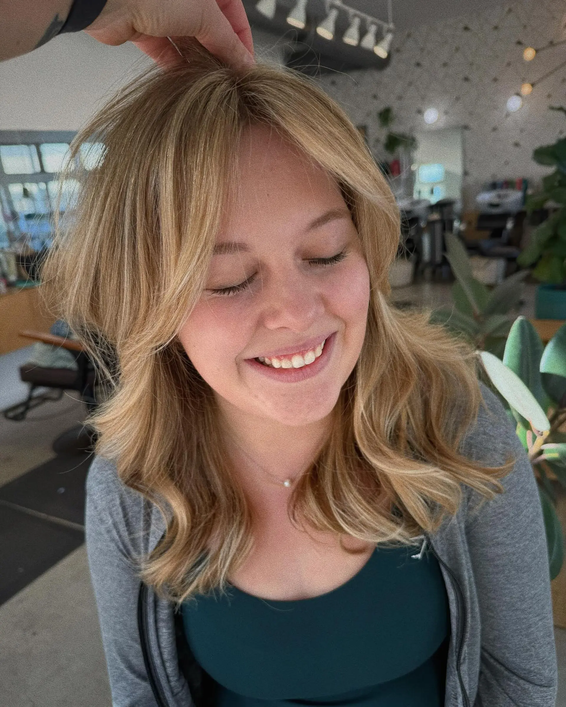 Medium-length warm golden blonde hair featuring dimensional highlights, soft layered waves, and face-framing curtain bangs. 1
