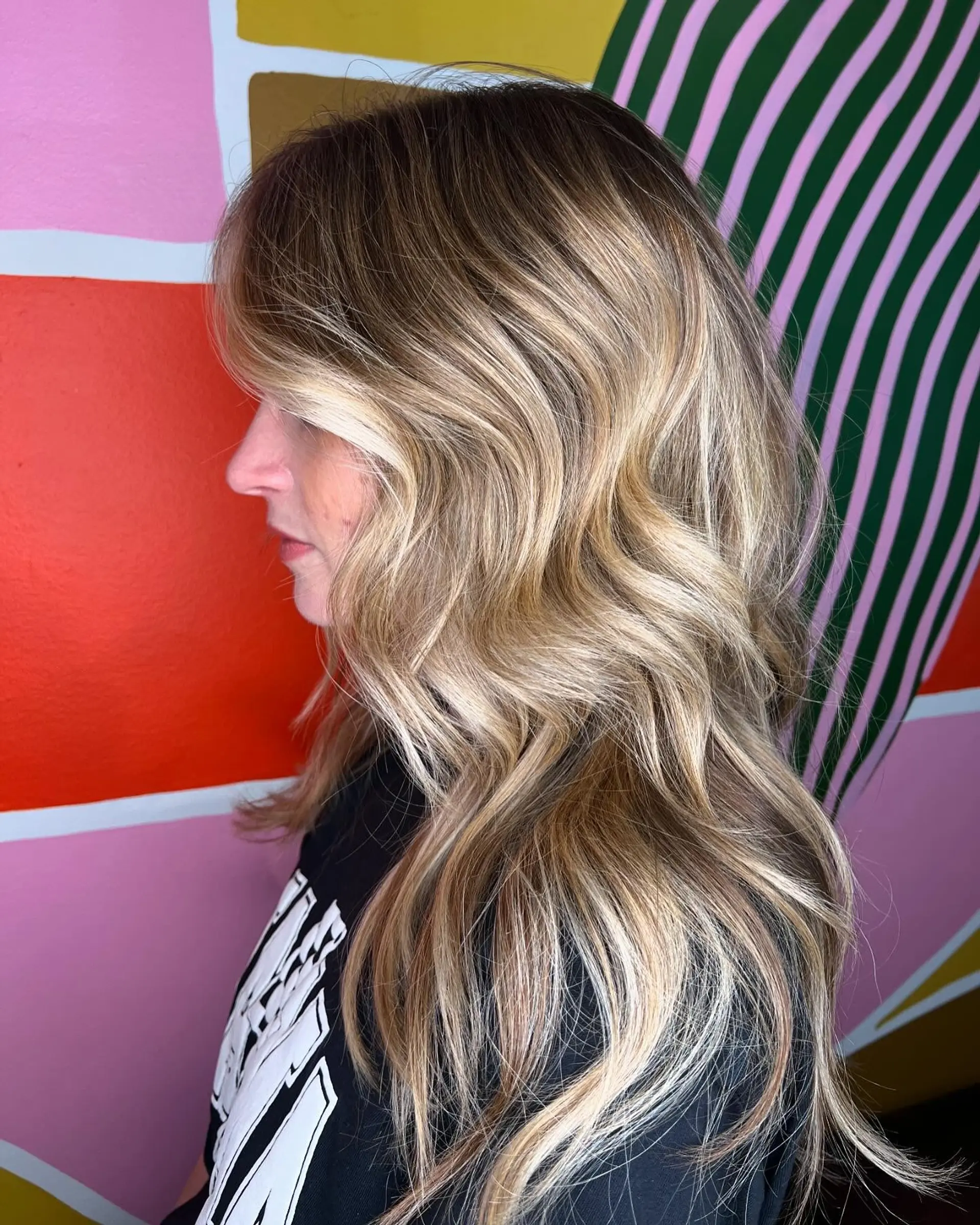 Long layered hair styled with loose waves featuring dimensional blonde balayage and soft face-framing highlights. 1