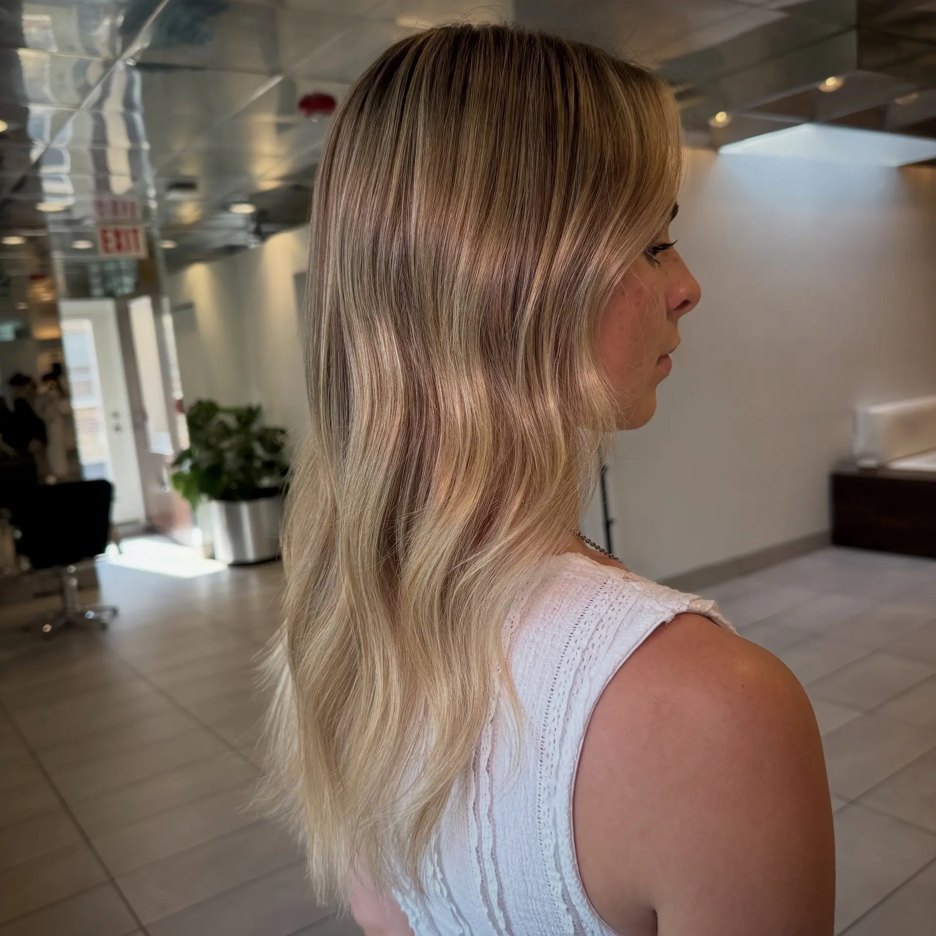 Long dimensional blonde hair styled in soft, relaxed waves with a seamless root melt. 1