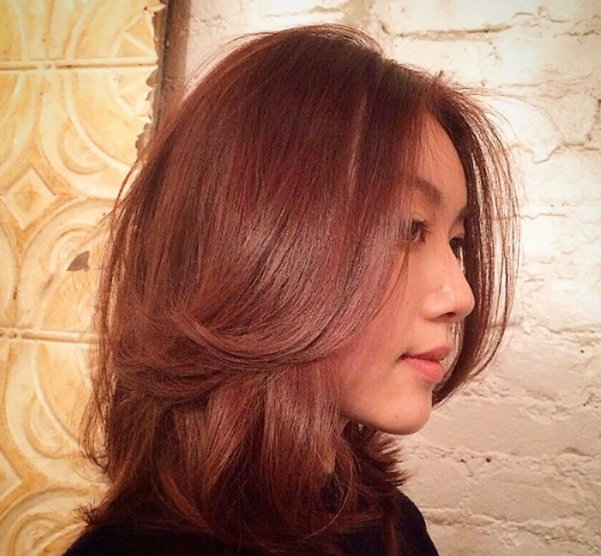 Medium length wavy auburn hair with voluminous layers that create a soft, side-swept appearance and gentle texture.