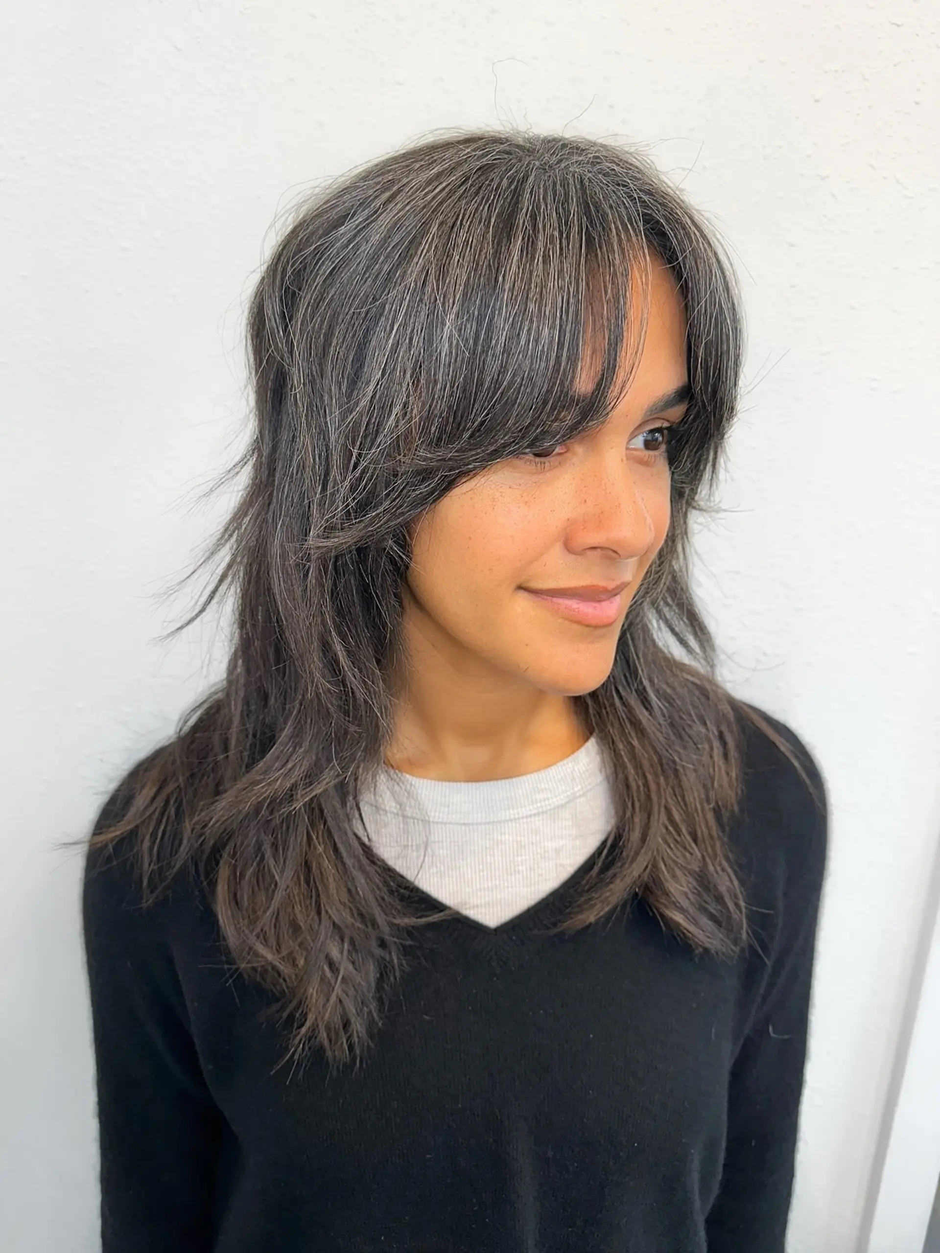 A medium-length shag haircut with soft curtain bangs and feathered face-framing layers. 1
