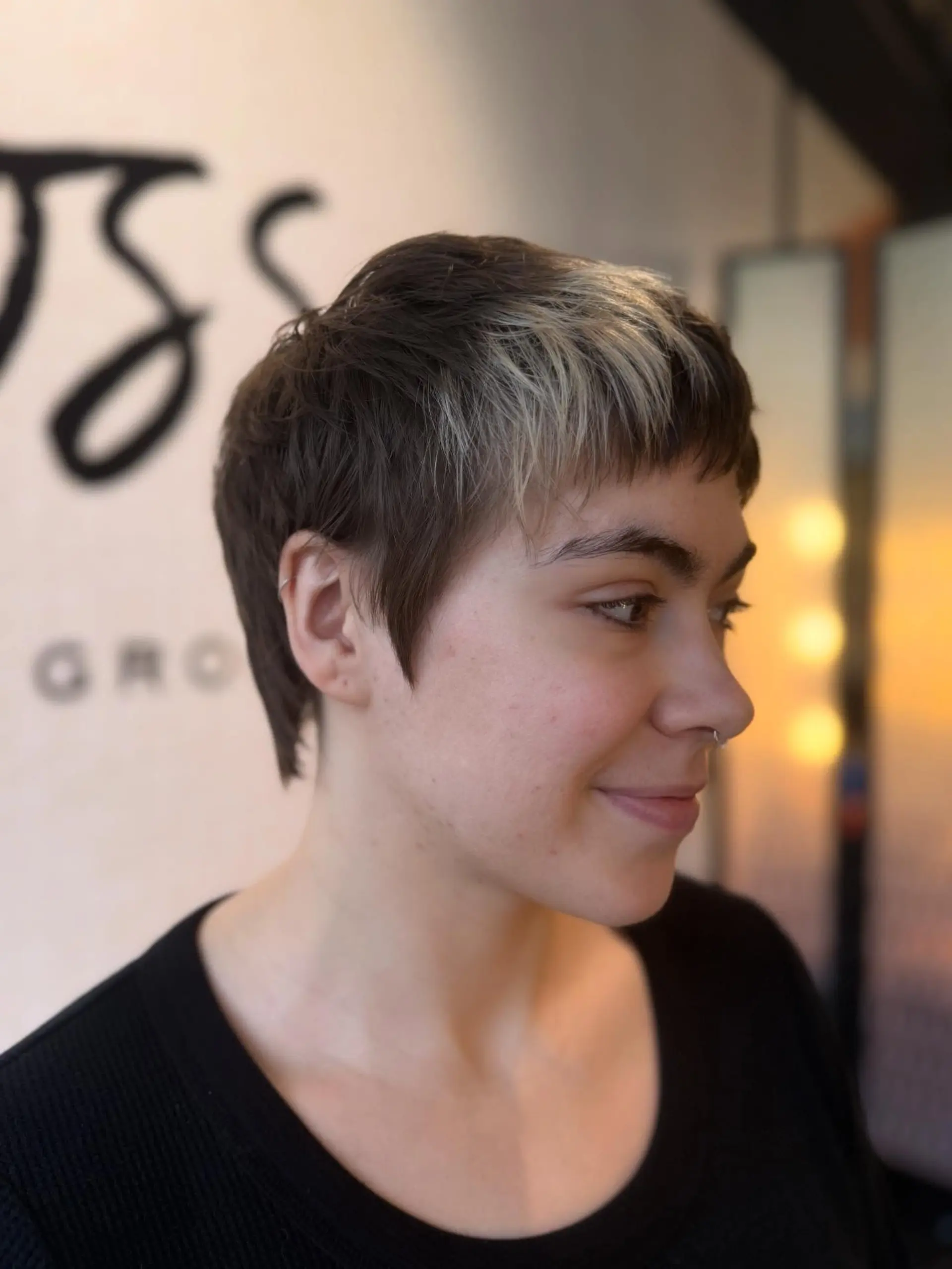 A textured, short razor cut featuring choppy micro bangs with a contrasting blonde fringe accent and softly tapered sides. 1