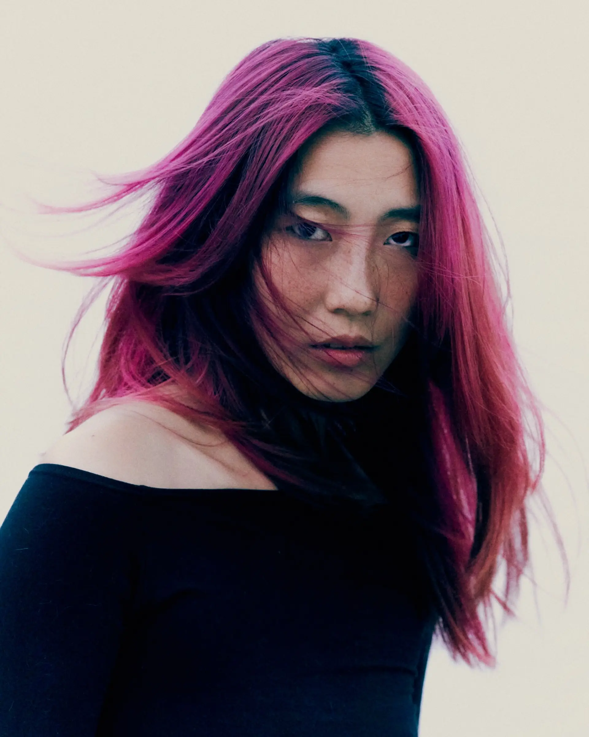 Vibrant magenta-pink hair with subtle dark roots and a layered cut, styled with windblown texture. 1