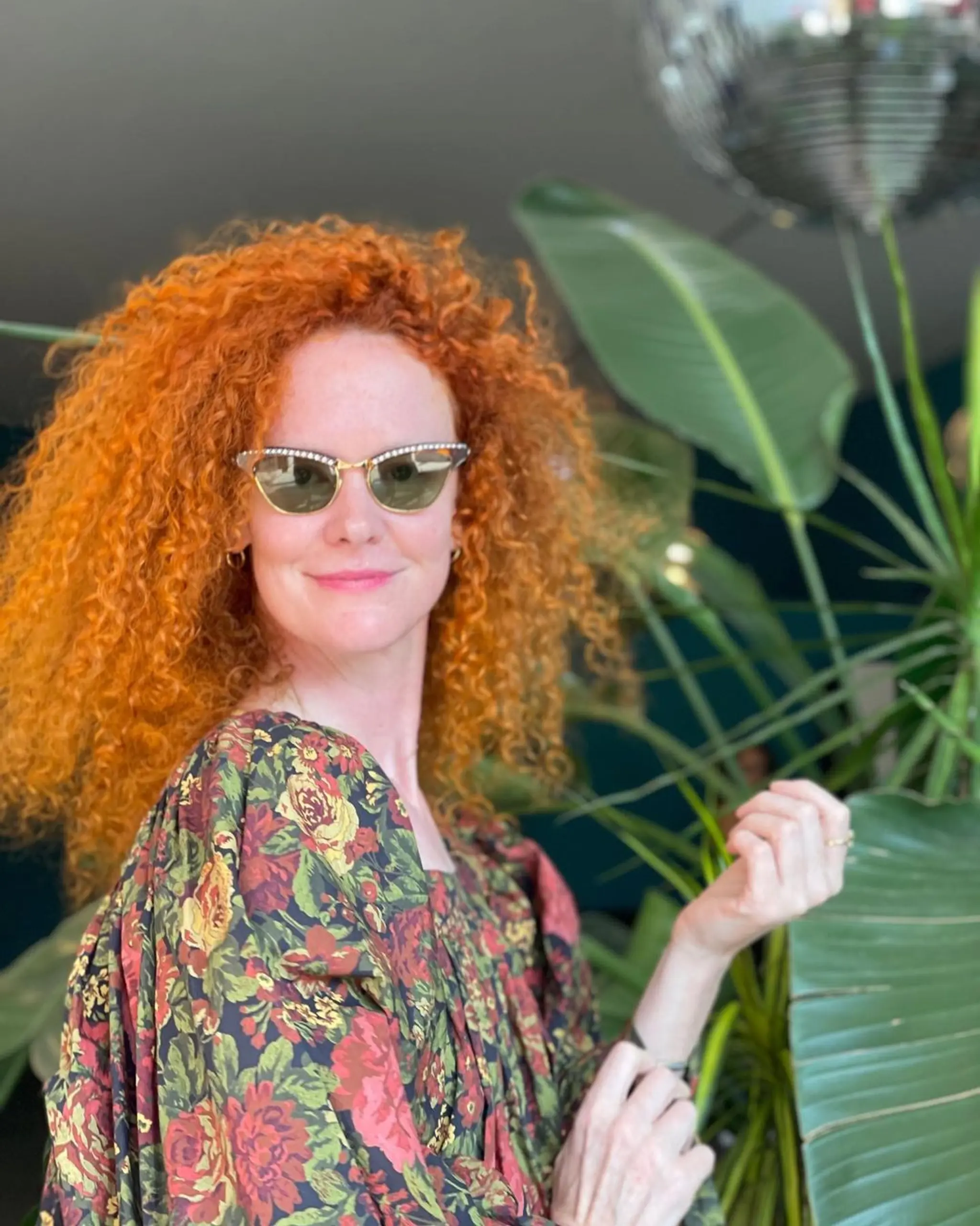 Long, vibrant red curly hairstyle with bold volume and natural curls, creating a dynamic and textured appearance.