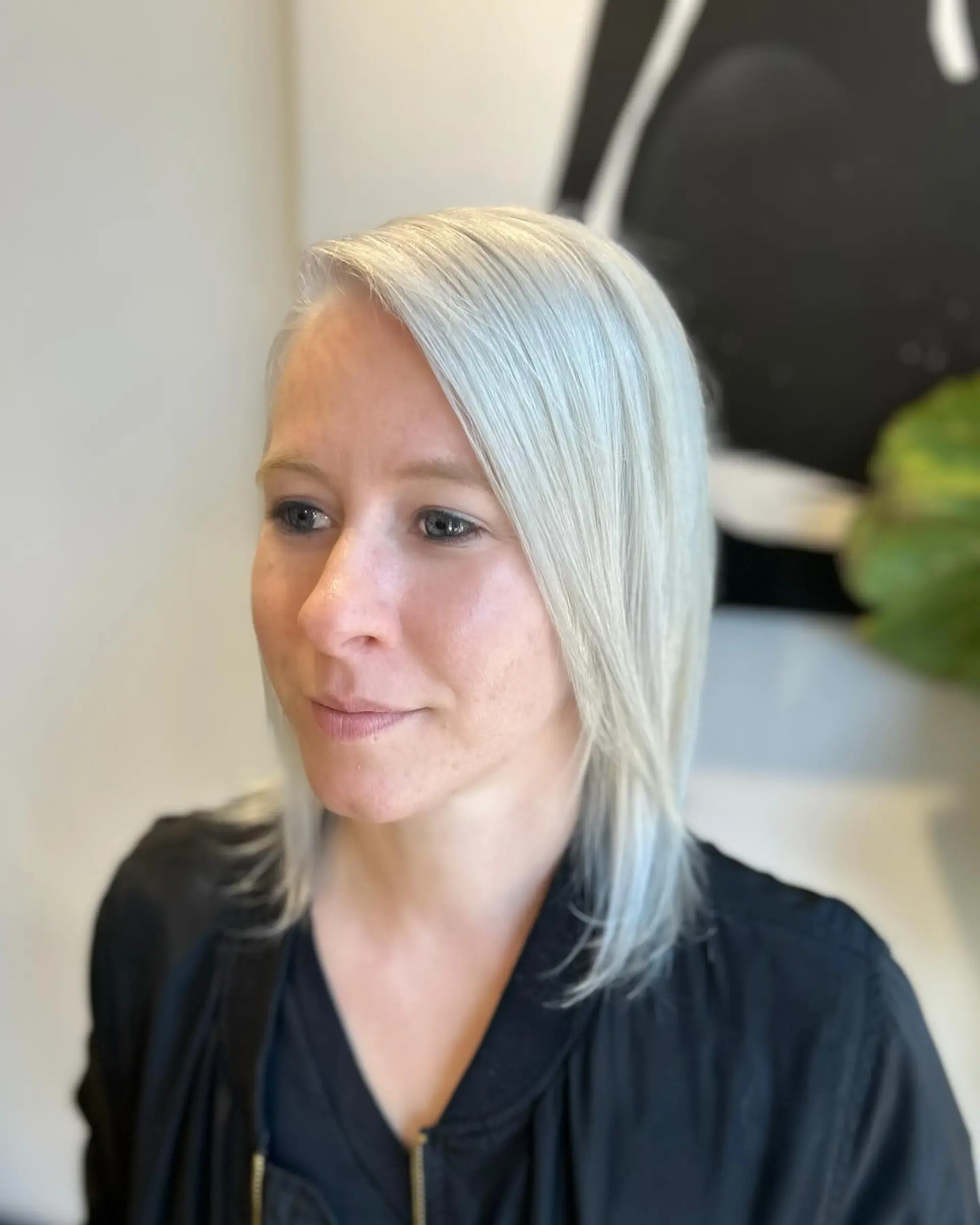 A sleek, shoulder-grazing medium lob in a bright, icy platinum blonde parted deeply to the side. 1