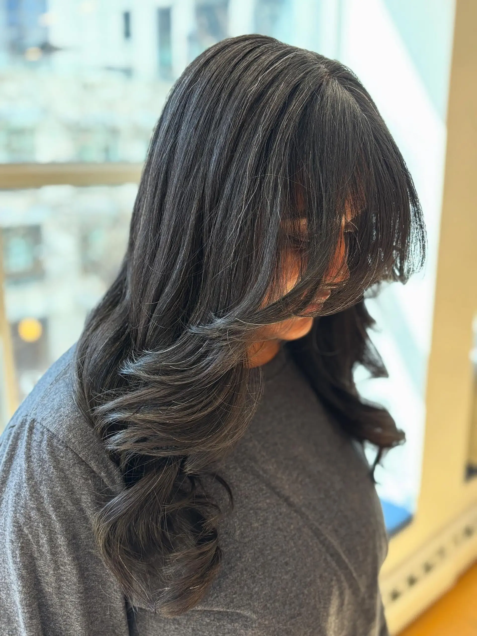 A long, layered hairstyle with face-framing curtain bangs. 2