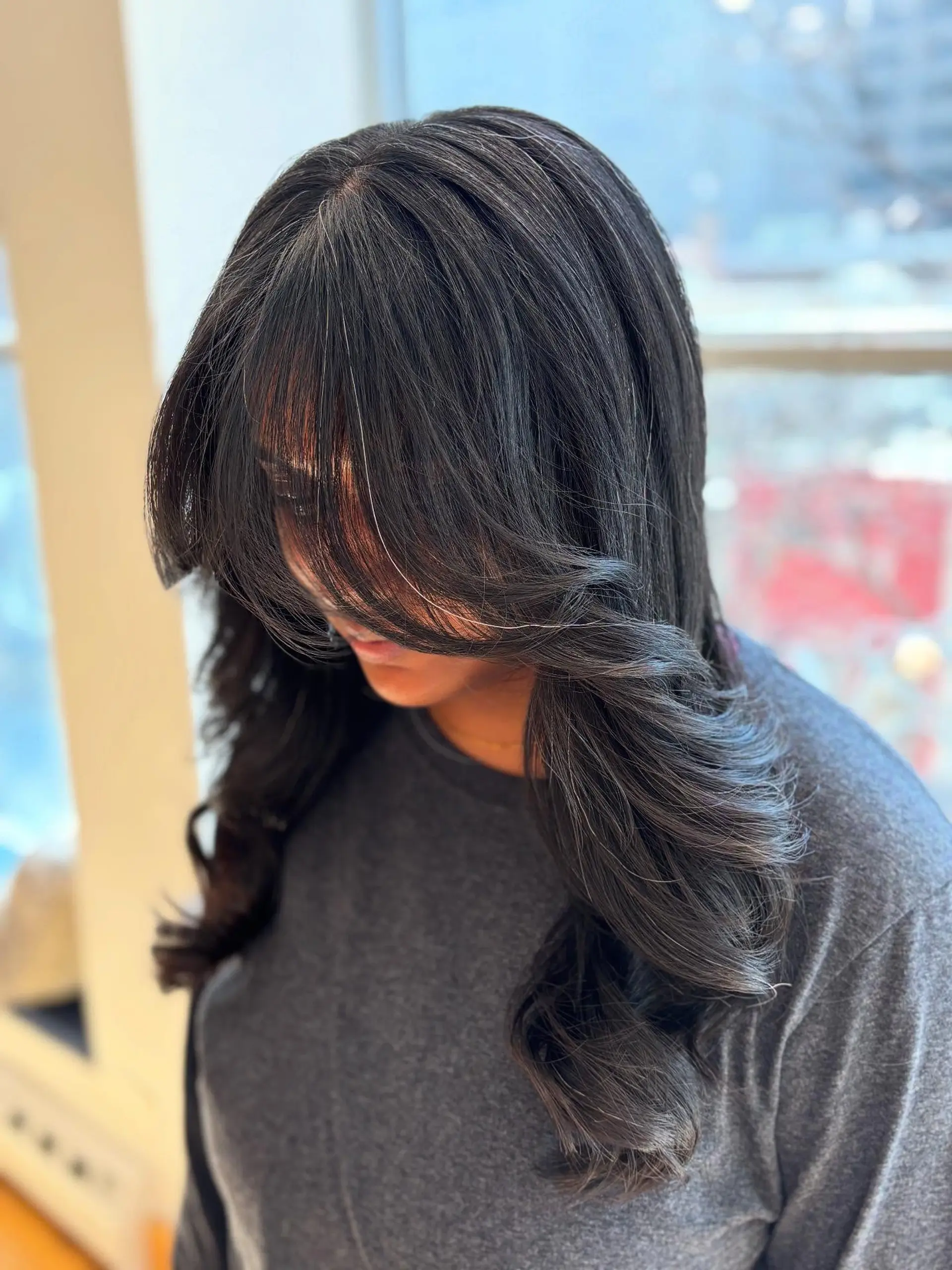 A long, layered hairstyle with face-framing curtain bangs. 3