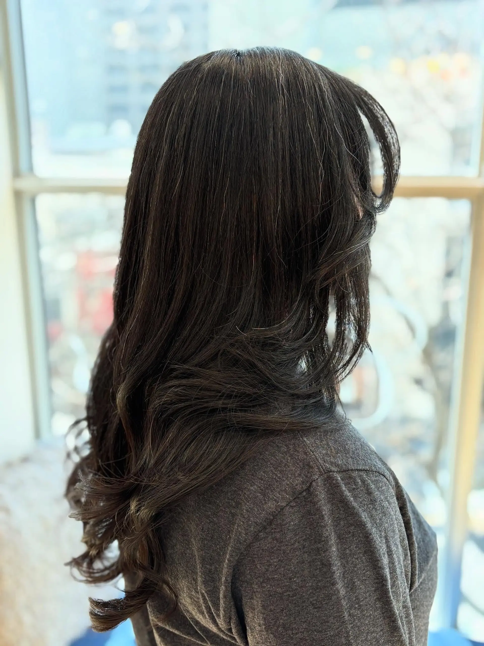 A long, layered hairstyle with face-framing curtain bangs. 4