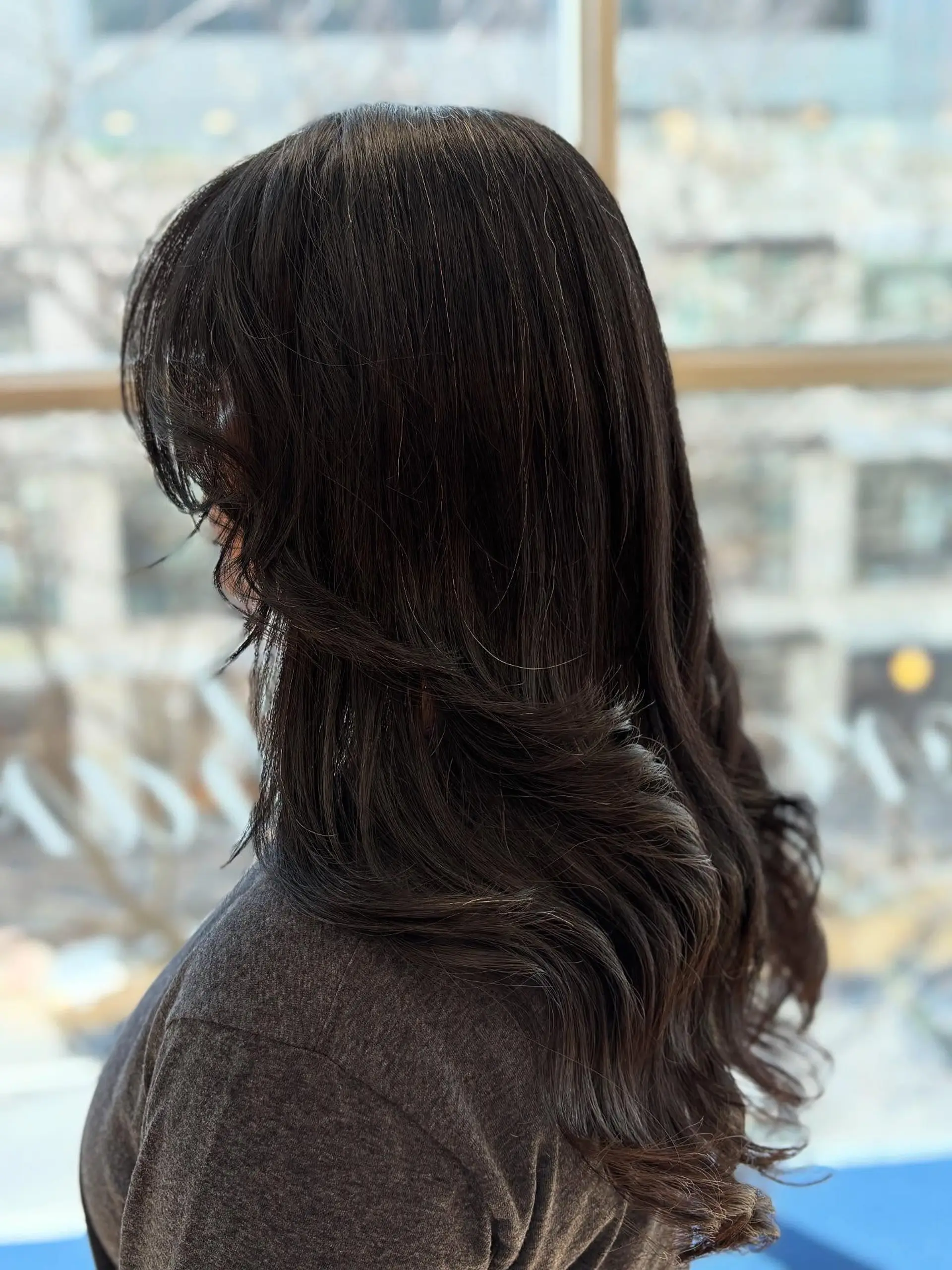 A long, layered hairstyle with face-framing curtain bangs. 5