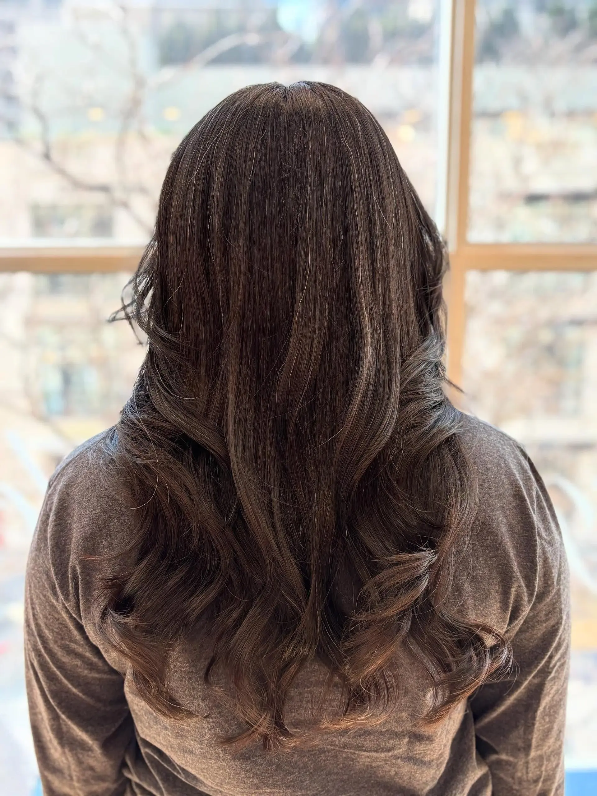 A long, layered hairstyle with face-framing curtain bangs. 6