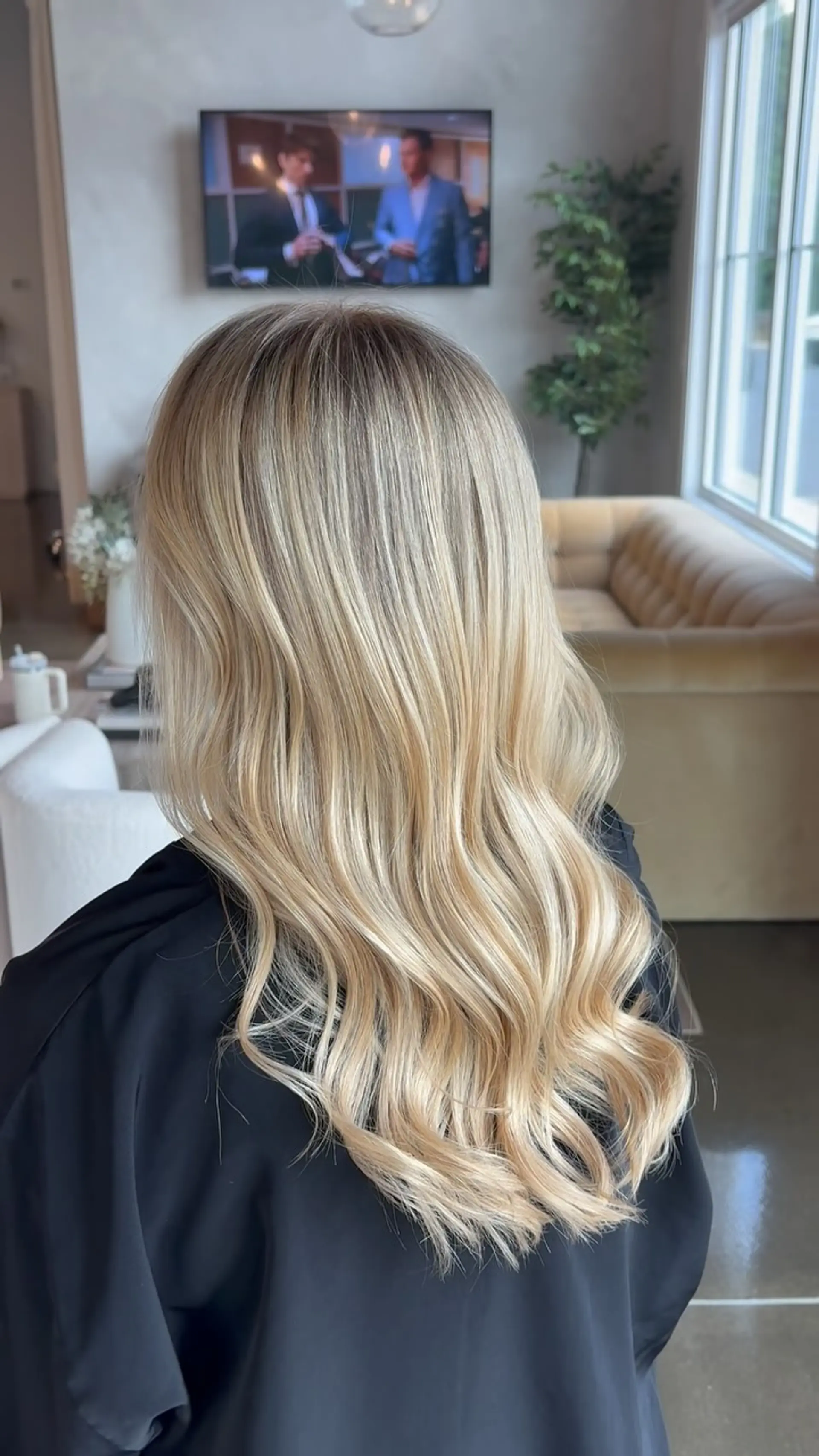 Long lived-in blonde hair featuring a shadowed root melted into bright, multi-tonal dimensional blonde highlights, styled in loose, polished waves. 1