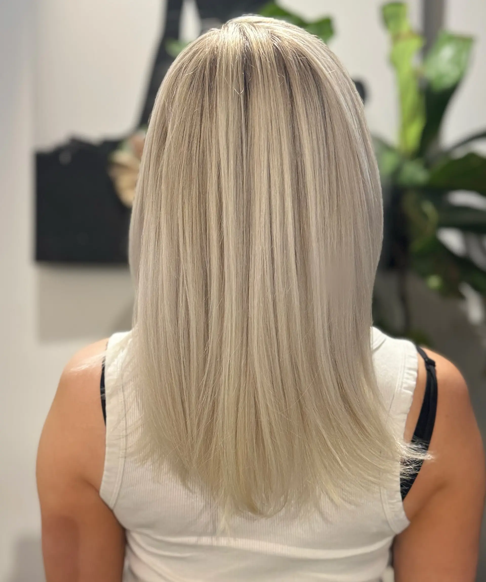 Sleek and straight bright platinum blonde hair cascading down the back with smooth, refined ends. 1