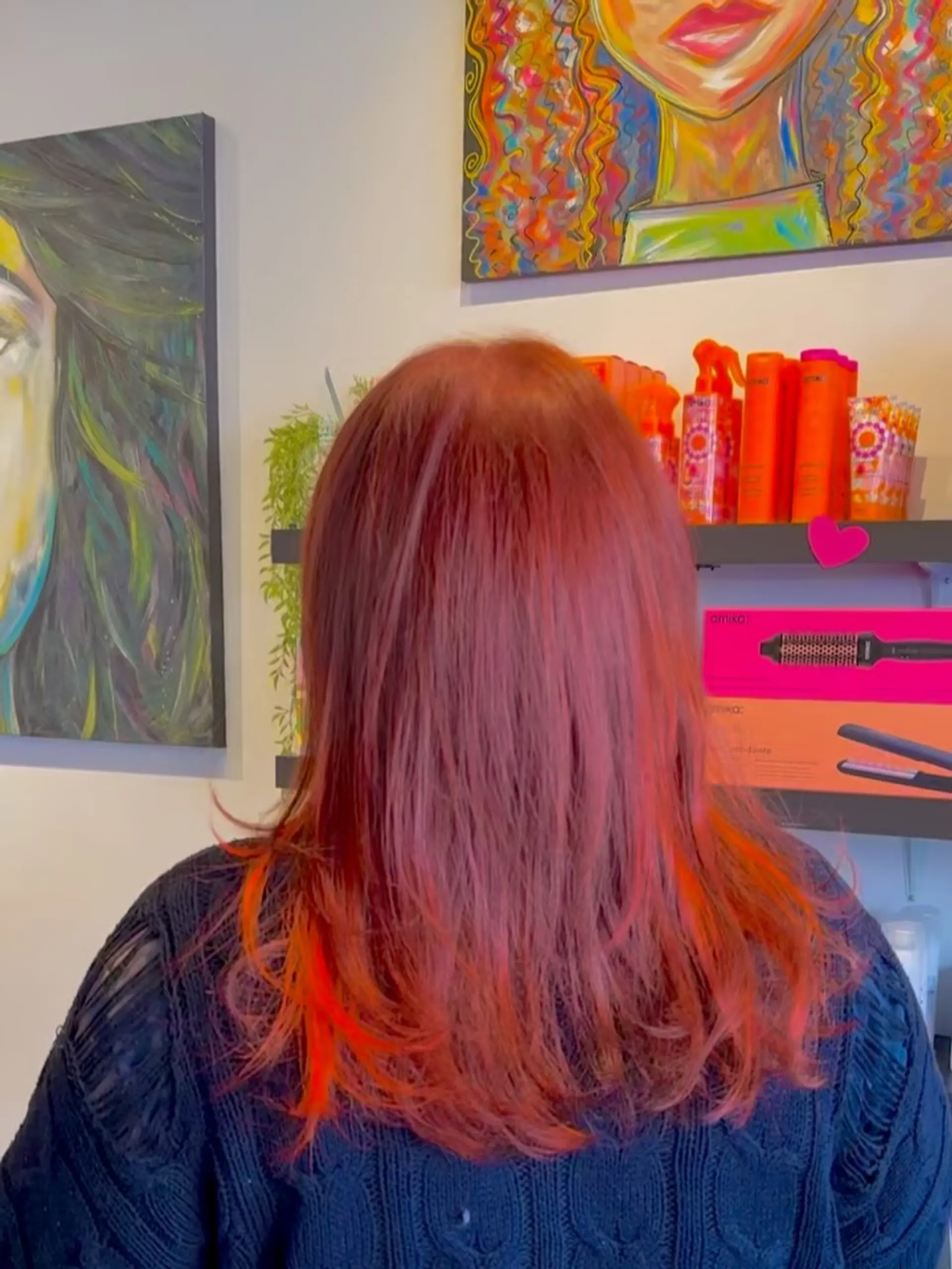 Medium-length textured mullet cut featuring vibrant crimson red hair with electric orange peekaboo accents. 1